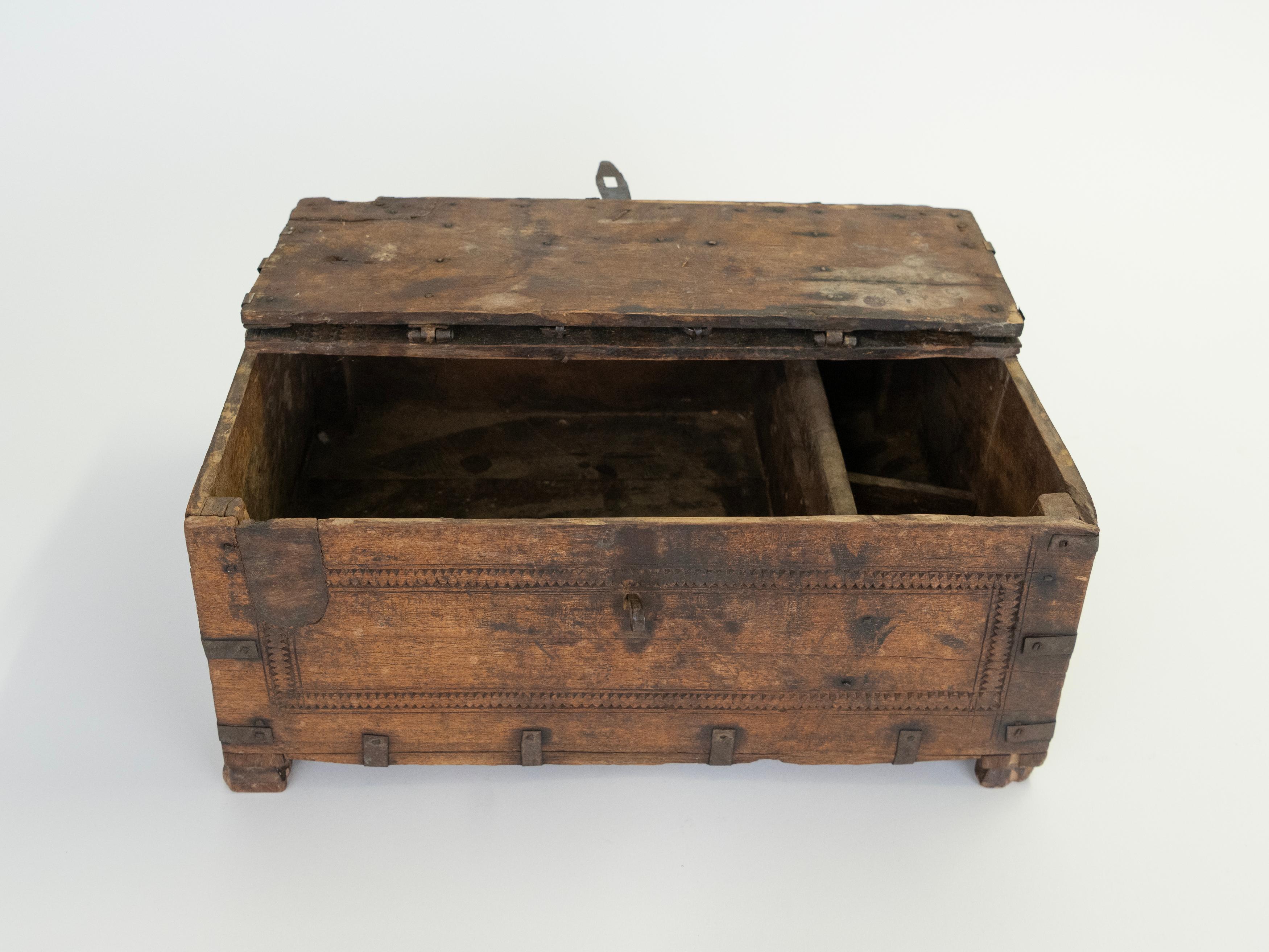 Coffre de rangement en bois dur sculpté du début du 20e siècle, originaire d'Afghanistan, qui a conservé ses ferrures et ses accessoires d'origine. La forme rectangulaire est définie par une surface profondément patinée et une bordure géométrique