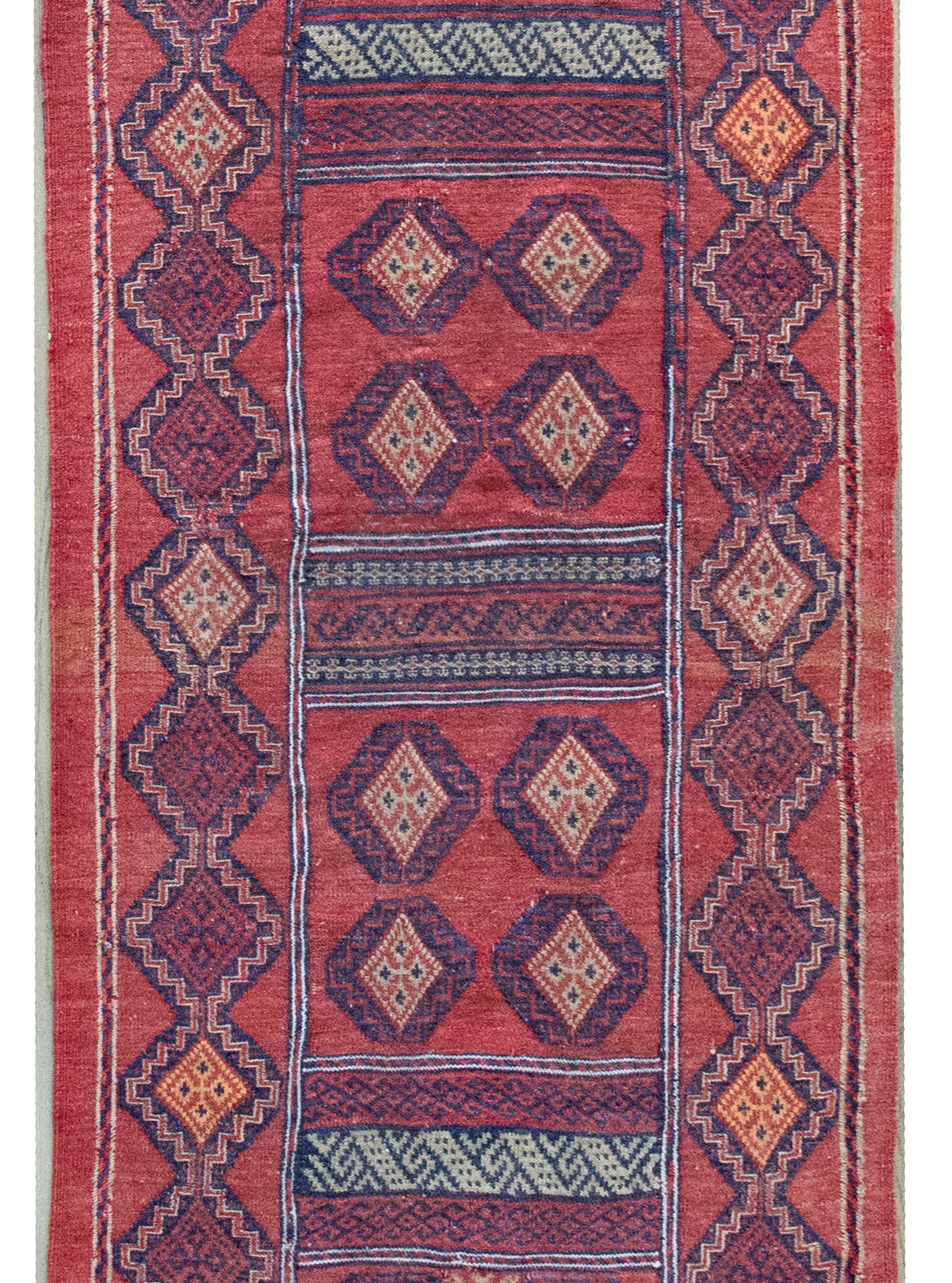 Dieser afghanische Sumac-Teppich aus dem frühen 20. Jahrhundert zeichnet sich durch ein täuschend einfaches, aber raffiniert gewebtes geometrisches Muster aus, bei dem sich Rauten um das Feld herum wiederholen - jeweils eingerahmt von einem
