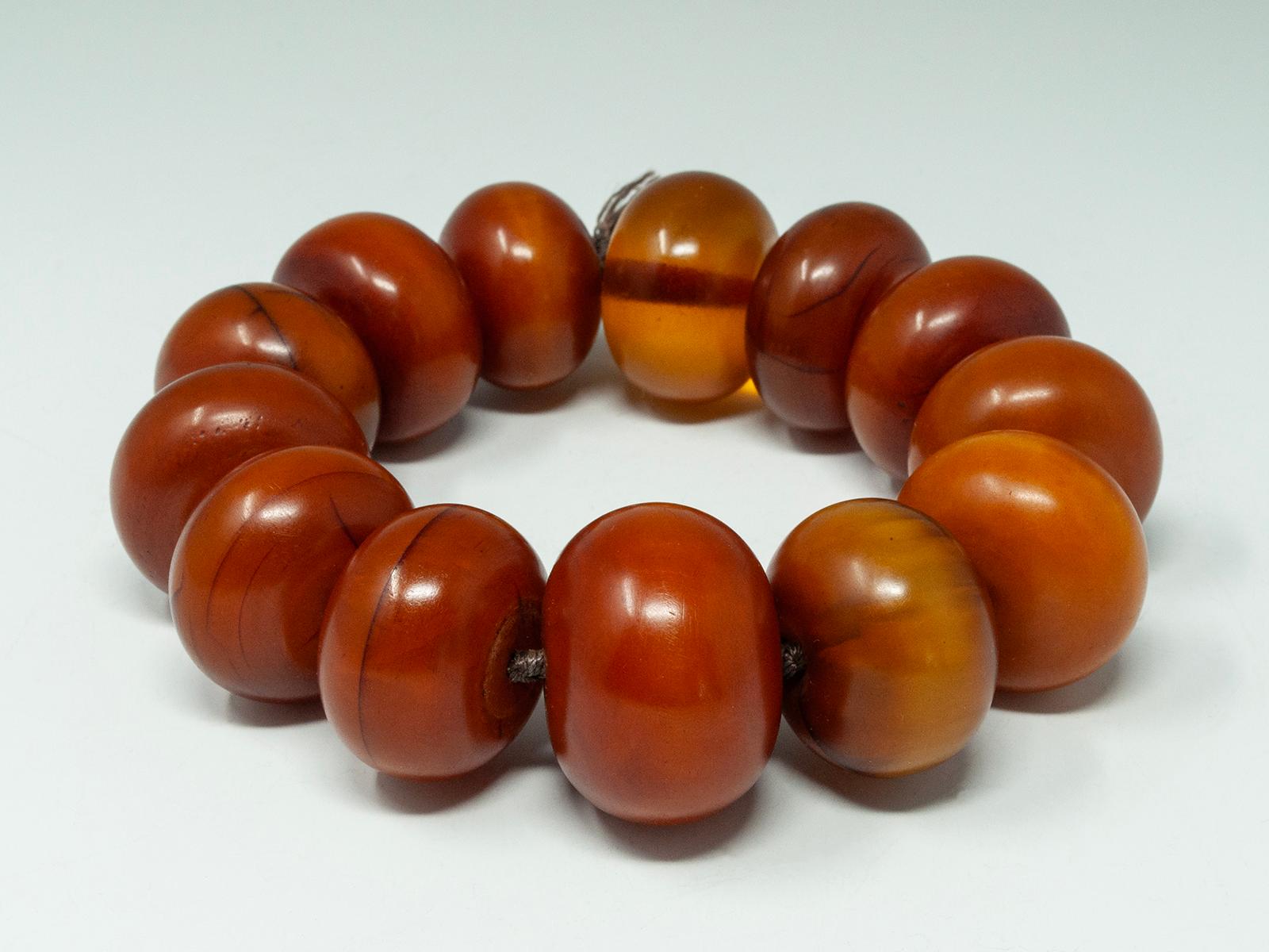 Afrikanisches Bakelit-Perlenarmband aus dem frühen 20.

Ein dramatisches Armband aus 13 Perlen aus afrikanischem Bernstein aus Phenolharz (Bakelit), aufgereiht auf Seiden- oder Nylonschnur mit Knoten zwischen jeder Perle. Sie ist nicht elastisch,