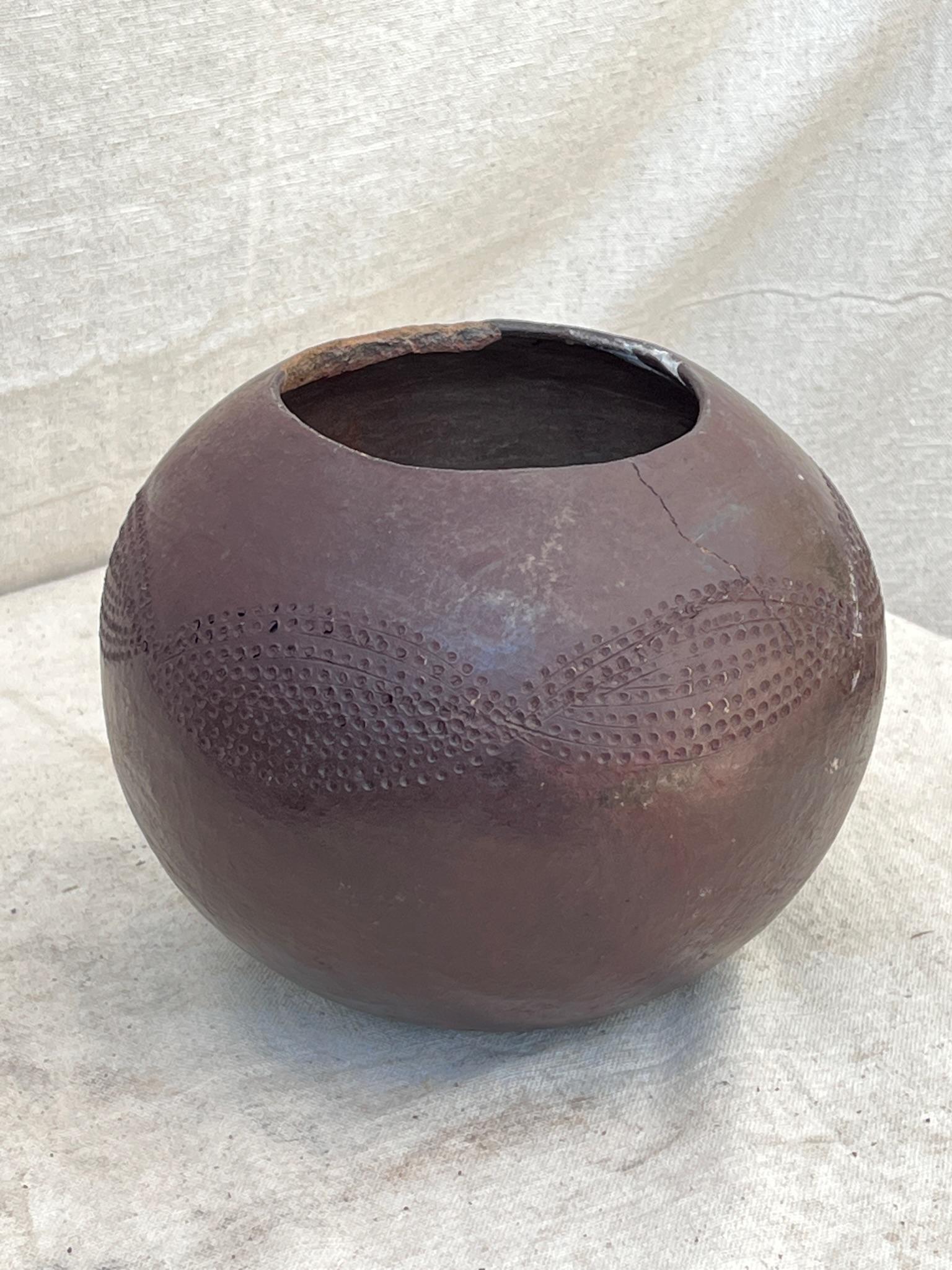 The early 20th-century South African clay beer pot from the Zulu culture is a spherical beer pot showcasing faintly incised decorations at its midsection, offering a glimpse into the artistry of that era.

Measures: 8” W X 7.5