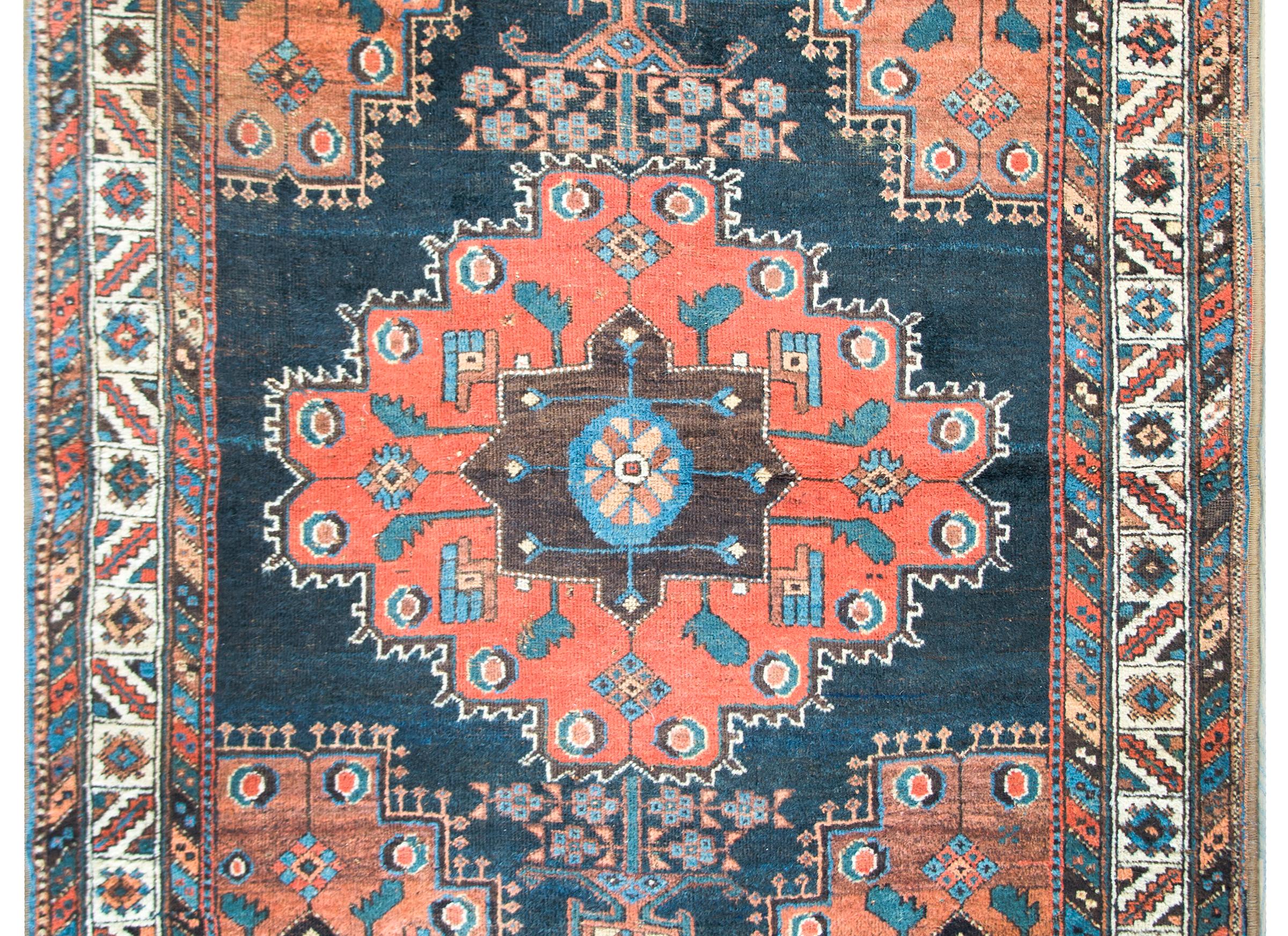 An outstanding early 20th century Persian Afshar rug with a large central medallion with the most wonderful stylized flowers and leaves all woven in indigo, orange, brown, and coral colored wool, and surrounded by a gorgeous border with several