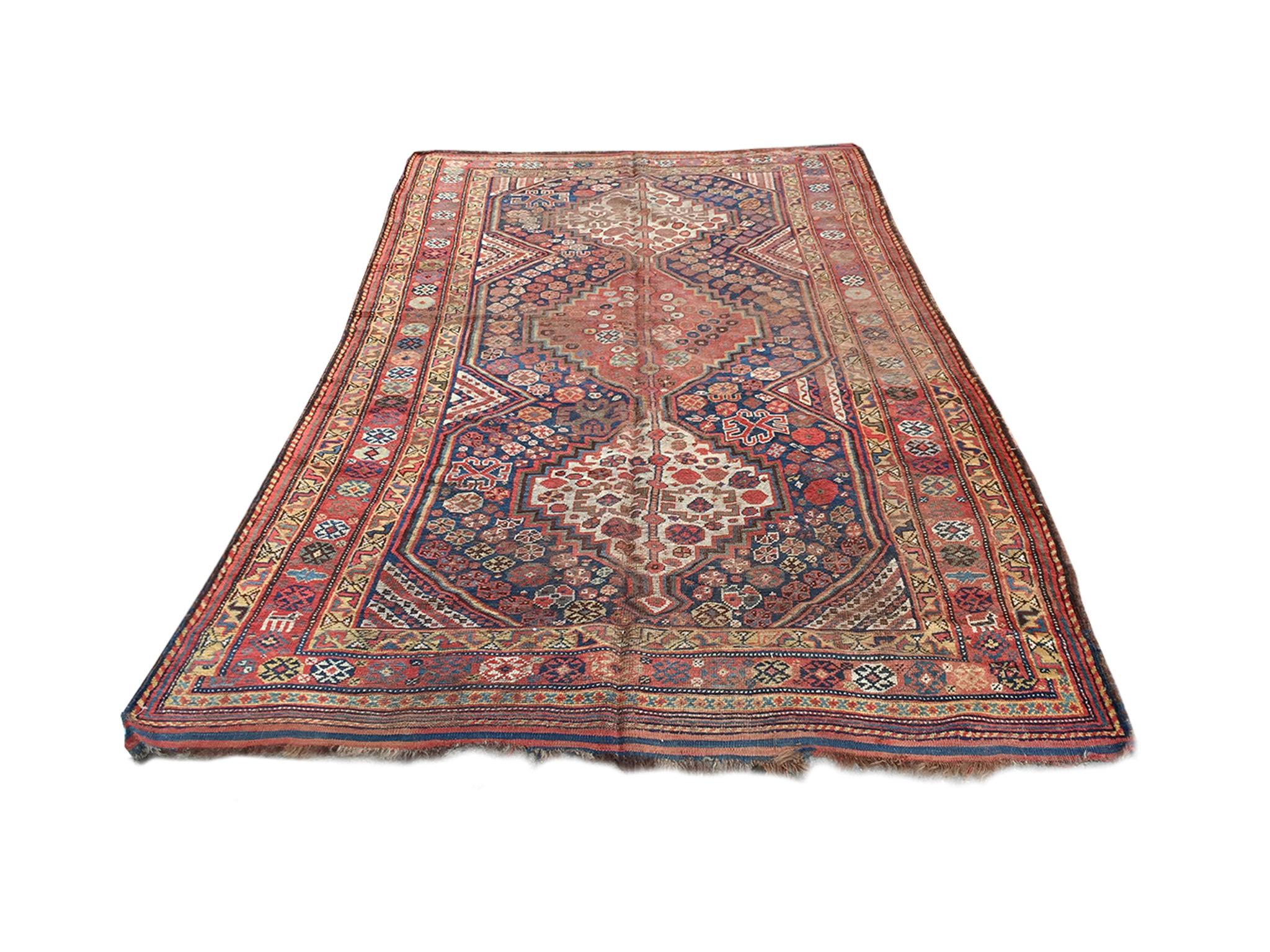 A remarkable handwoven early 20th century Afshar rug. Bold palette of reds, pinks, pale yellows, and blues. The rug's design consists of a central field with a column of three medallions. Floral-like geometric shapes are arranged in clusters within