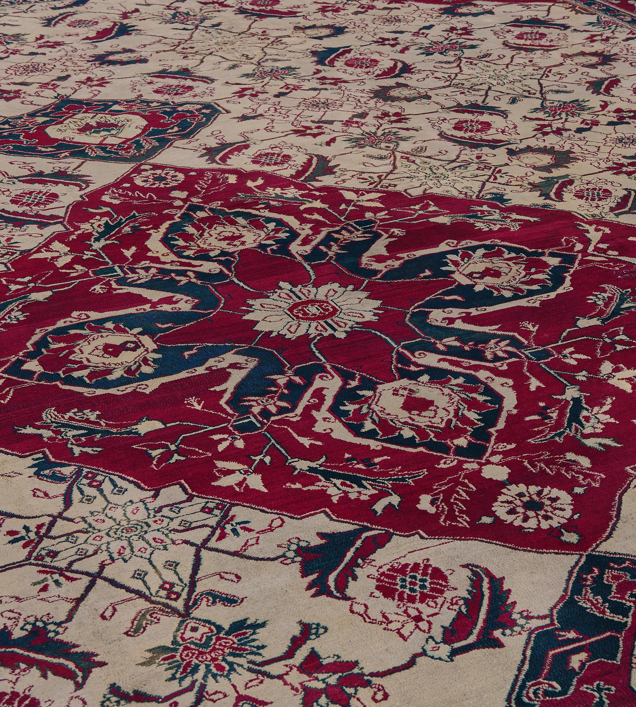 This antique traditional hand-woven Indian Agra rug has a shaded eu-de-nil field of broad ornate herati pattern, enclosing a ruby lozenge medallion with inner cusped motif and issuing scrolling delicate vines, in a refined ruby scrolling palmettes