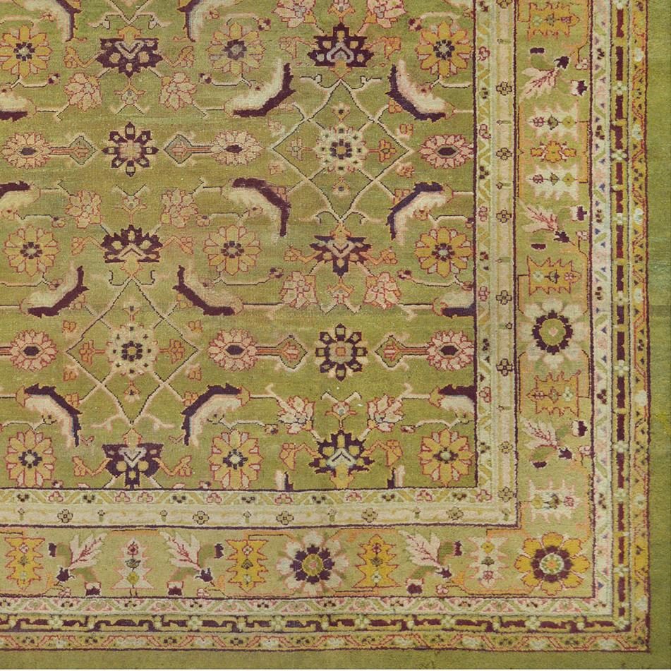 This traditional handwoven Indian Agra rug has a soft chartreuse field with overall angled herati pattern, in a green apple scrolling floral border, between a profusion of tonal vine stripes, plain outer chartreuse line stripe.