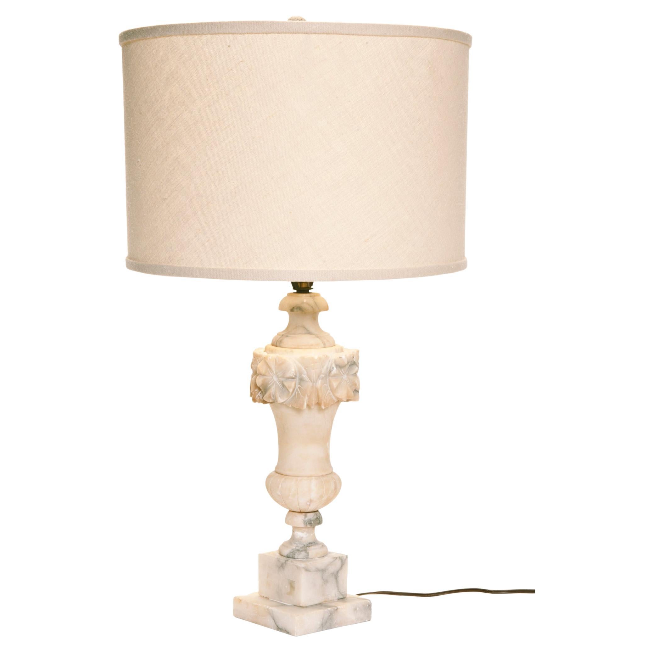  Early 20th Century hand-carved Italian alabaster table lamp from the
The baluster form lamp is topped with an urn embellished with a wreath of carved flowers. 
A linen drum shade is included. Rewired with new cord & socket.