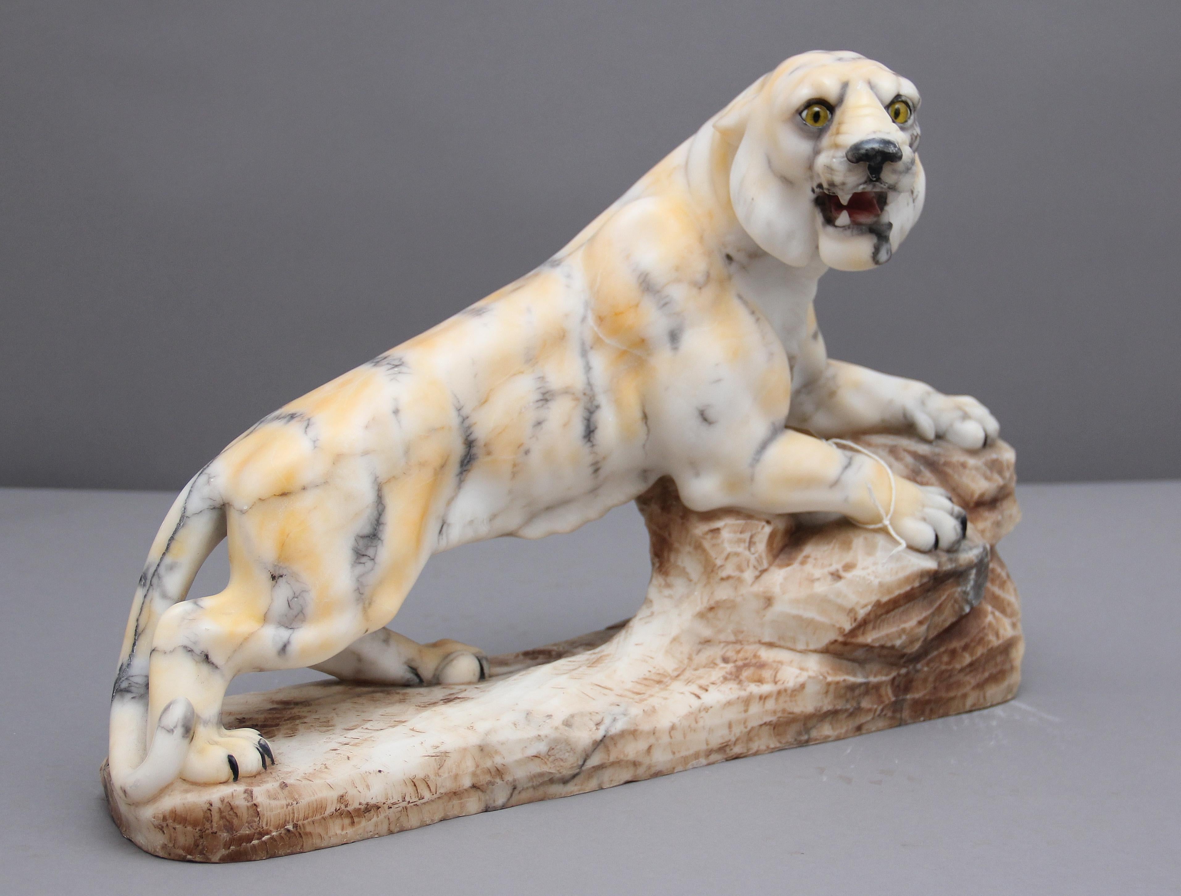 A highly decorative early 20th century alabaster tiger sculpture, the tiger is shown crouching on a tree trunk / large branch, superb quality and nice size with no losses and minor surface marks, circa 1920.
  