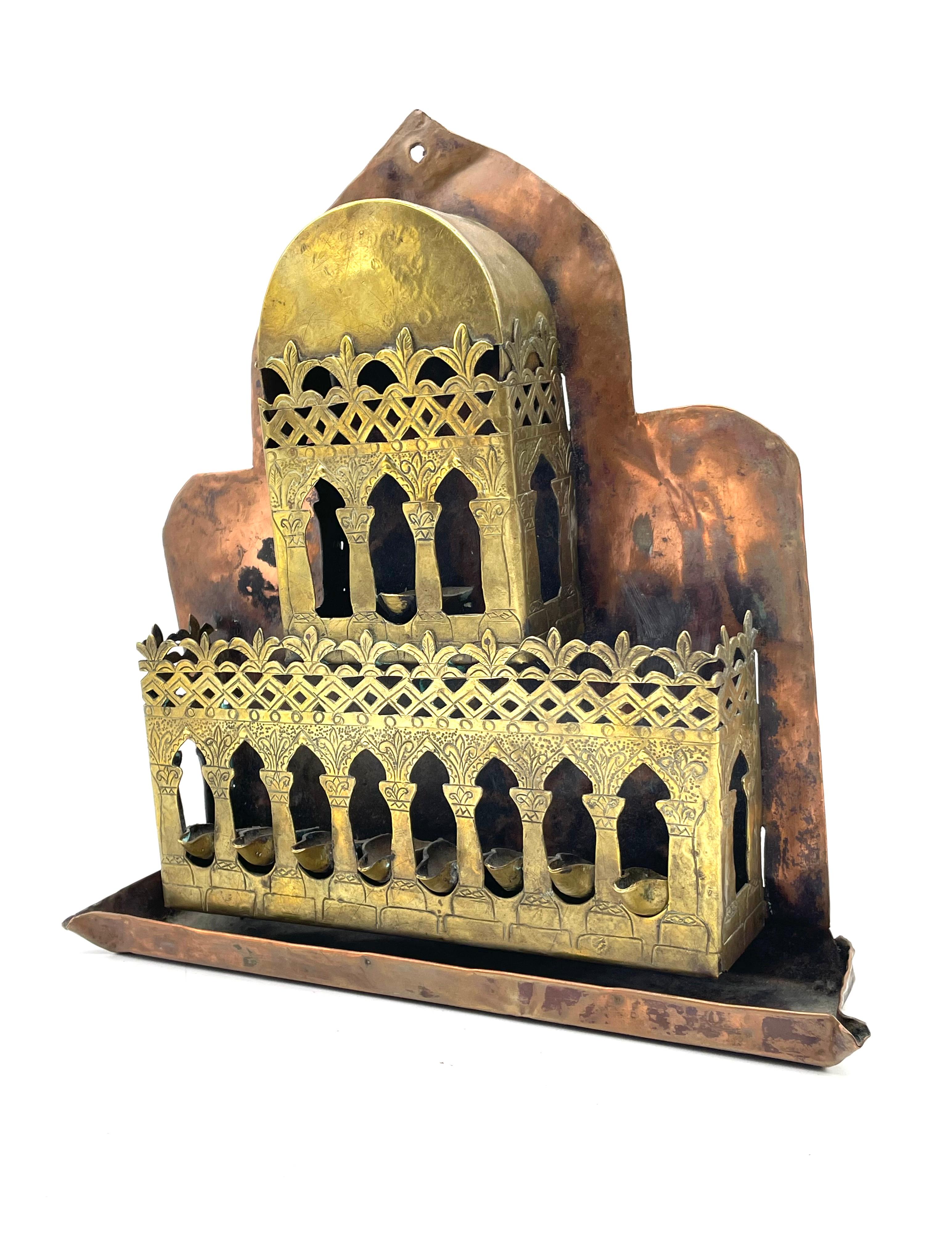 Hanukkah lamp shaped like a palace, surmounted by Islamic crescent. Made in Laghouat, Algeria. 
The Hanukkah lamp is made of two parts: a pierced and engraved brass in the shape of a palace, and a cooper sheet replicating the outlines of the