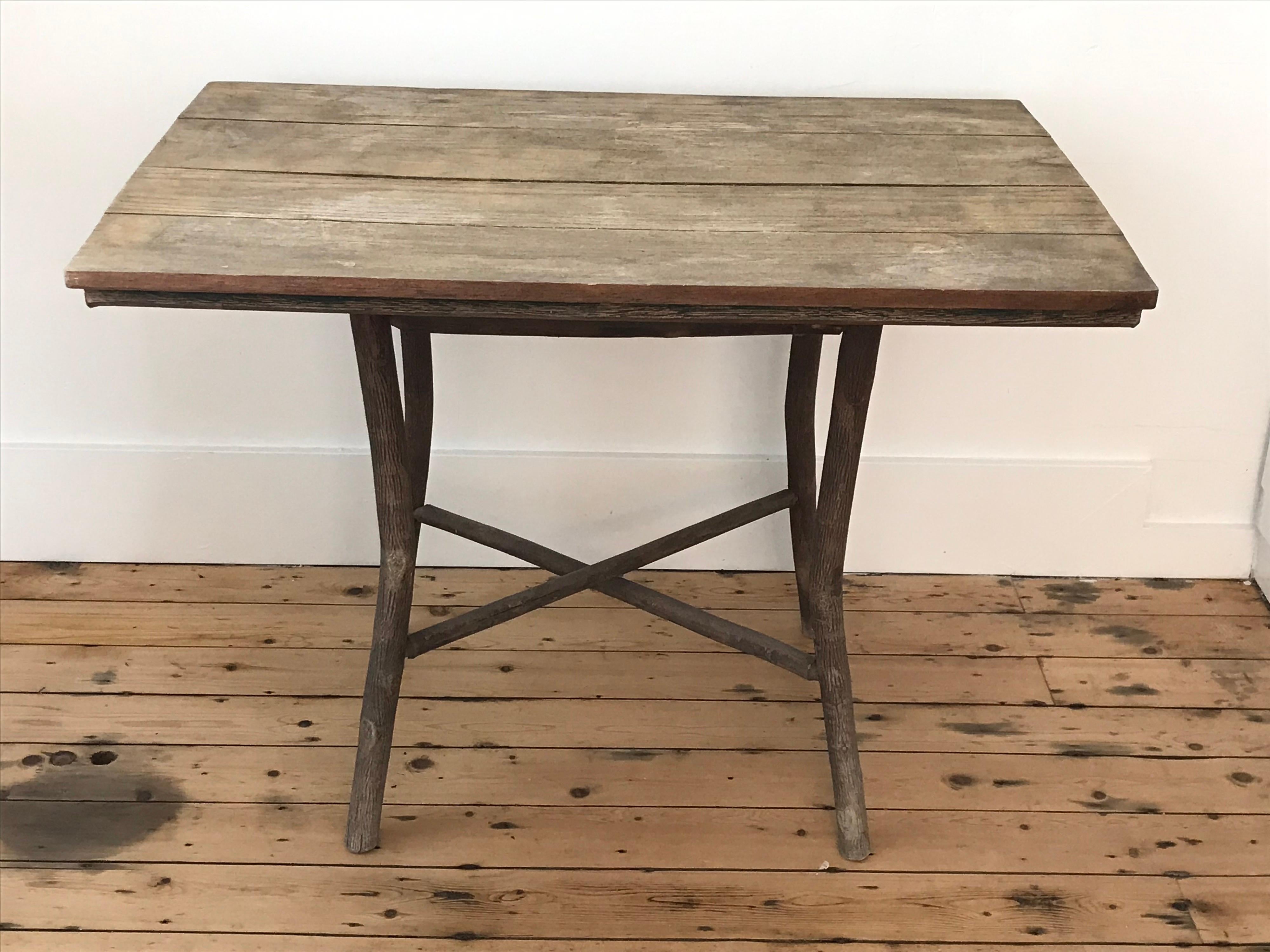 Early 20th Century rustic Folk Art American Adirondack camp table with open tree branch base and pine plank top.