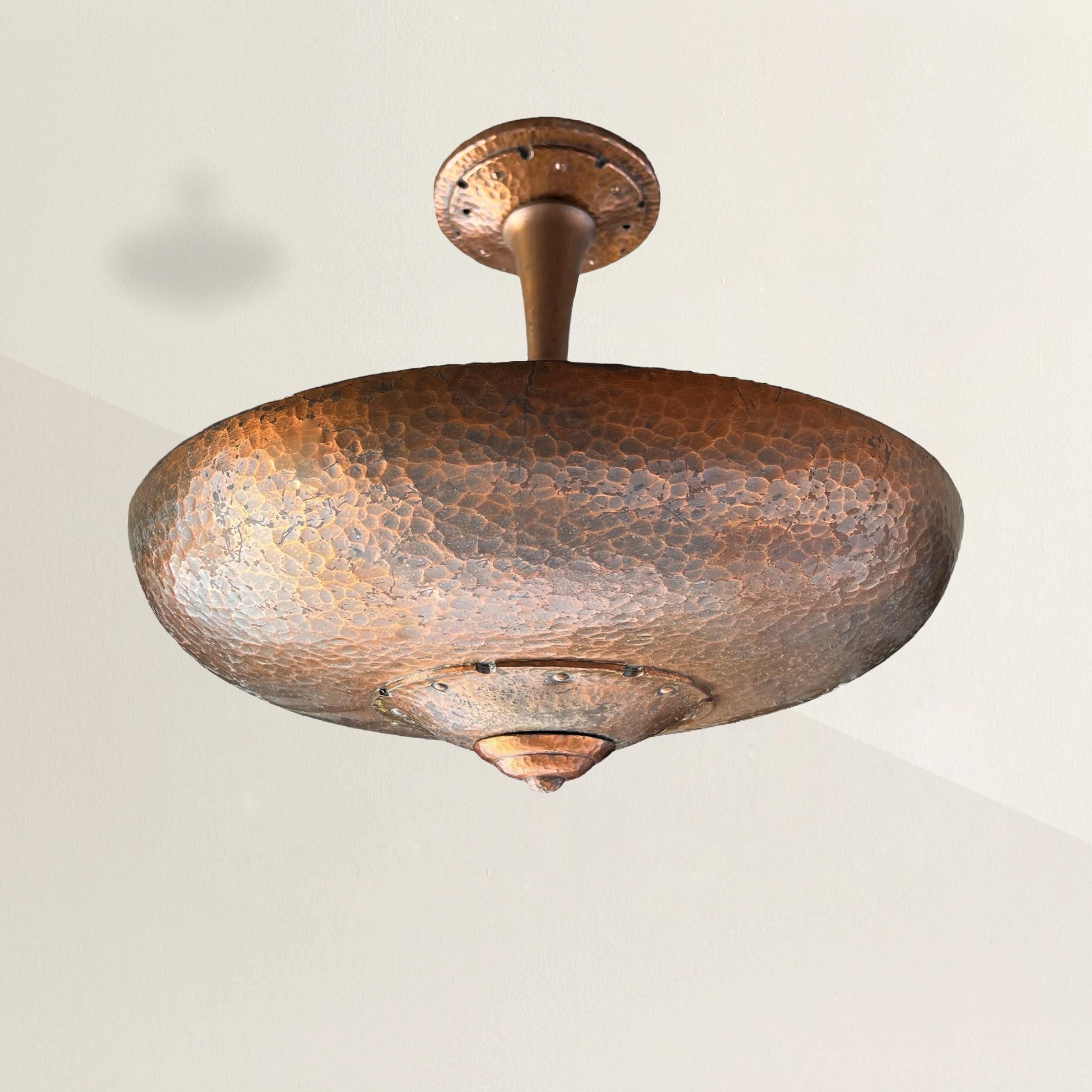 Celebrate the timeless allure of early 20th century industrial design with this stunning American Art Deco ceiling mounted uplight. Crafted with flair, its hammered copper shade suspended from a matching downrod exudes timeless elegance. The