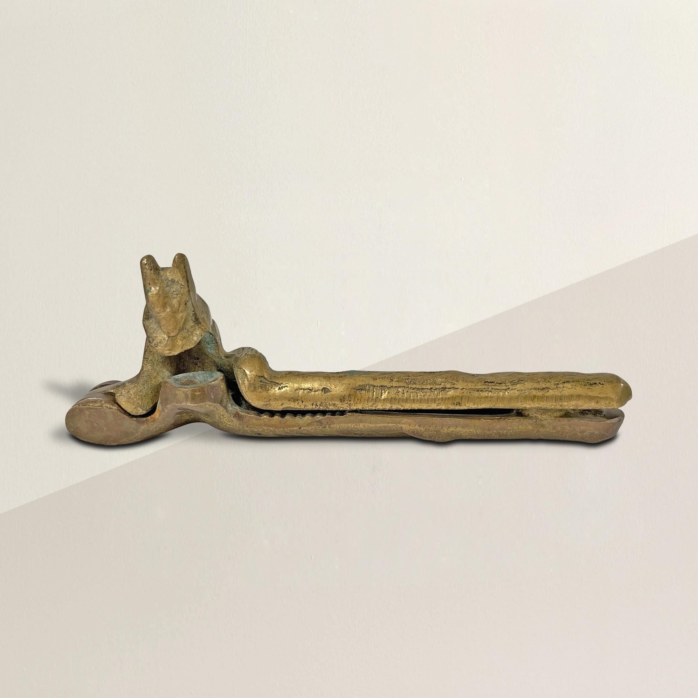 A whimsical early 20th century American cast bronze nut cracker depicting a squirrel on a log, where the nut rests on a stump and is held by the squirrel. So charming!