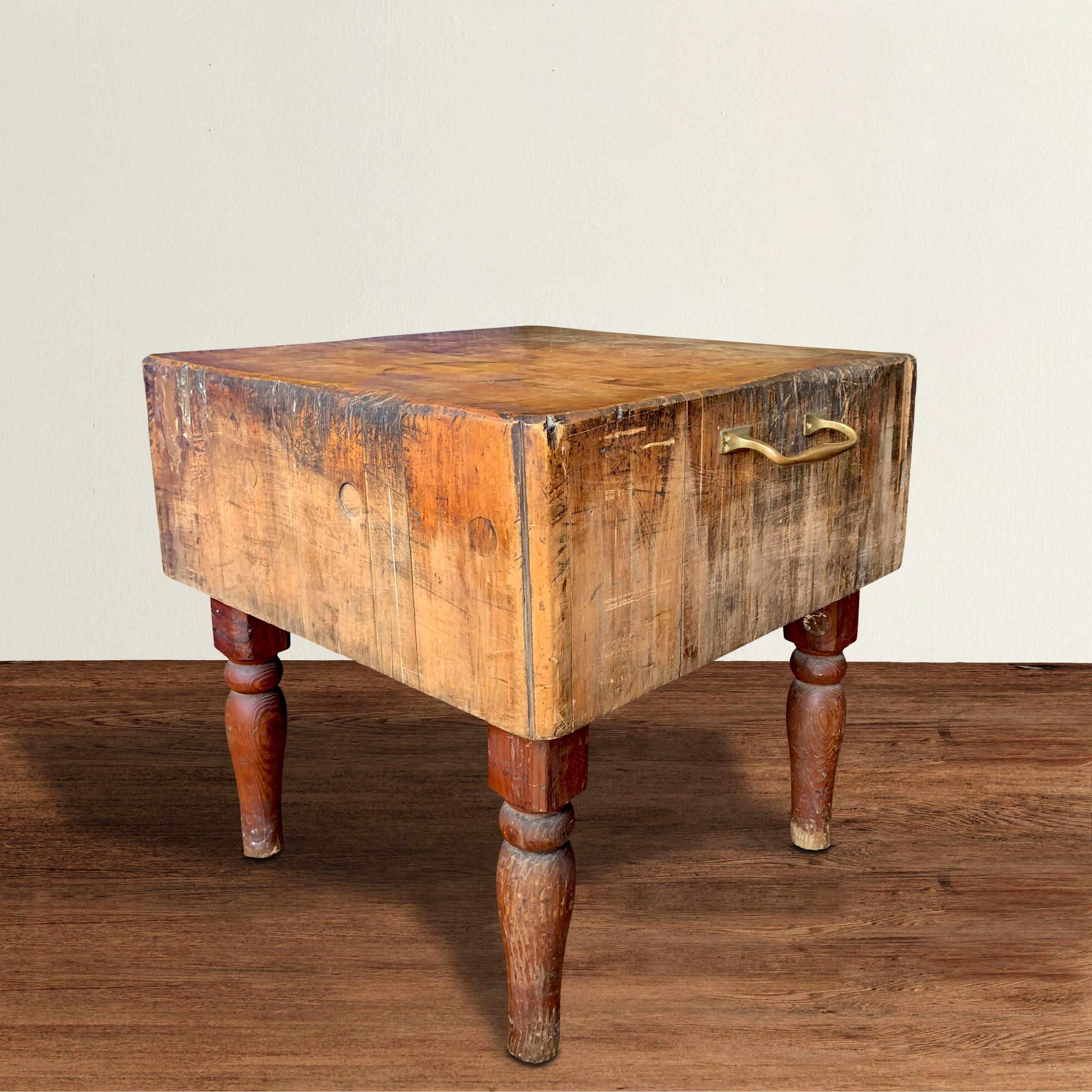 An incredible early 20th century American maple butcher block table constructed of hundreds of dove-tailed blocks puzzle-pieced together, with a bronze towel bar on one side, and with a wonderful patina only time can bestow. The block rests on four