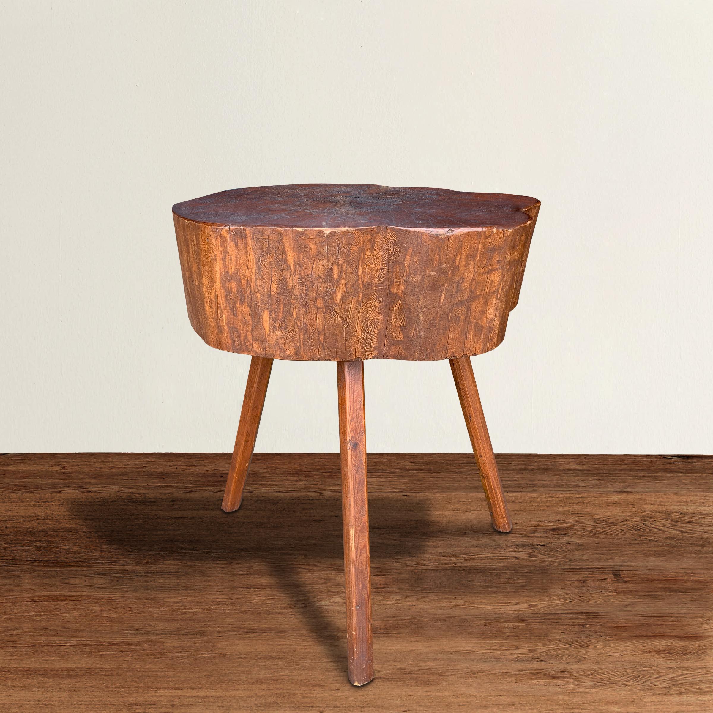 A quaint early 20th century American Primitive butcher block table made from a sliced log, with a beautiful stained dark red finish on top, and pine stick legs. Perfect as a pedestal, side table next to a sofa, or a bedside table. Could also be cut