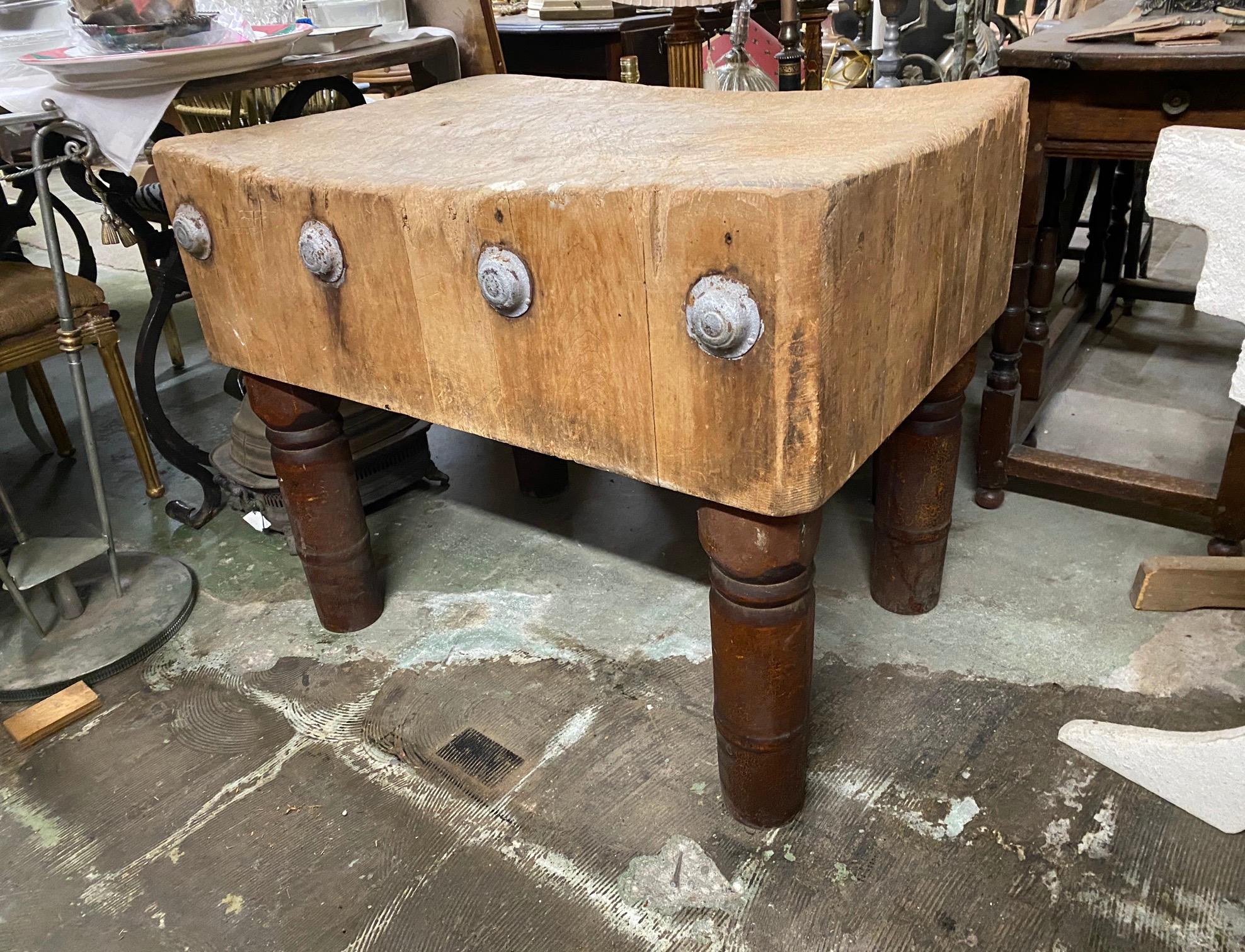 Early 20th century American maple butcher block table constructed of blocks, decorated with round zinc discs on one side, and with a wonderful patina. The block rests on four turned pine legs with of their original red paint. Table still functions
