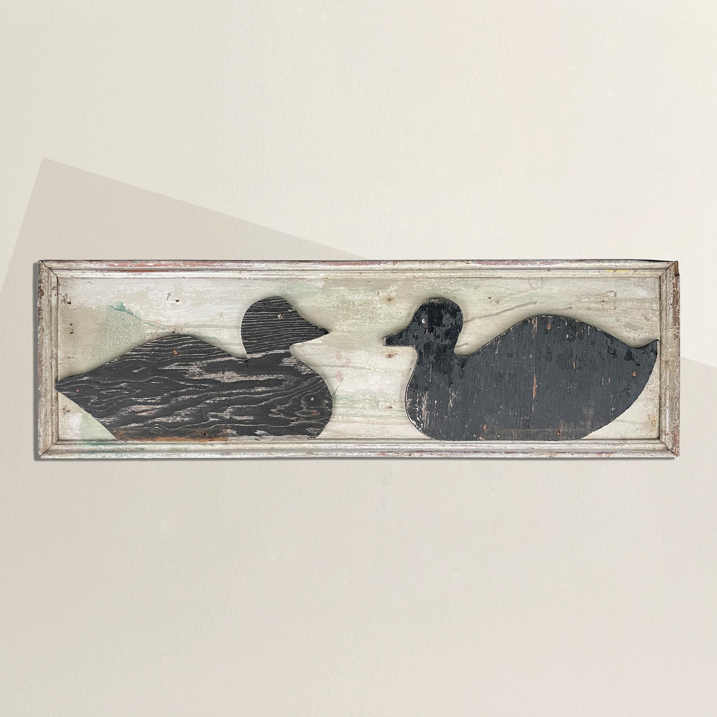 A charming early 20th century American folk art sign with two ducks, each cut out from ply wood and painted black, and attached to a white painted frame. Found in New England.