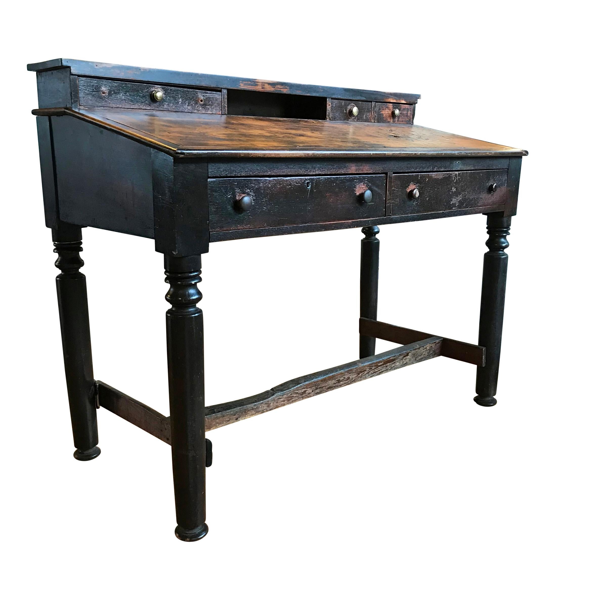 An early 20th century American factory foreman's desk with a slant top, three small drawers on top, and two large drawers below. The wear on the stretchers is remarkable, and clearly shows that the foreman stood on the left of the table for many