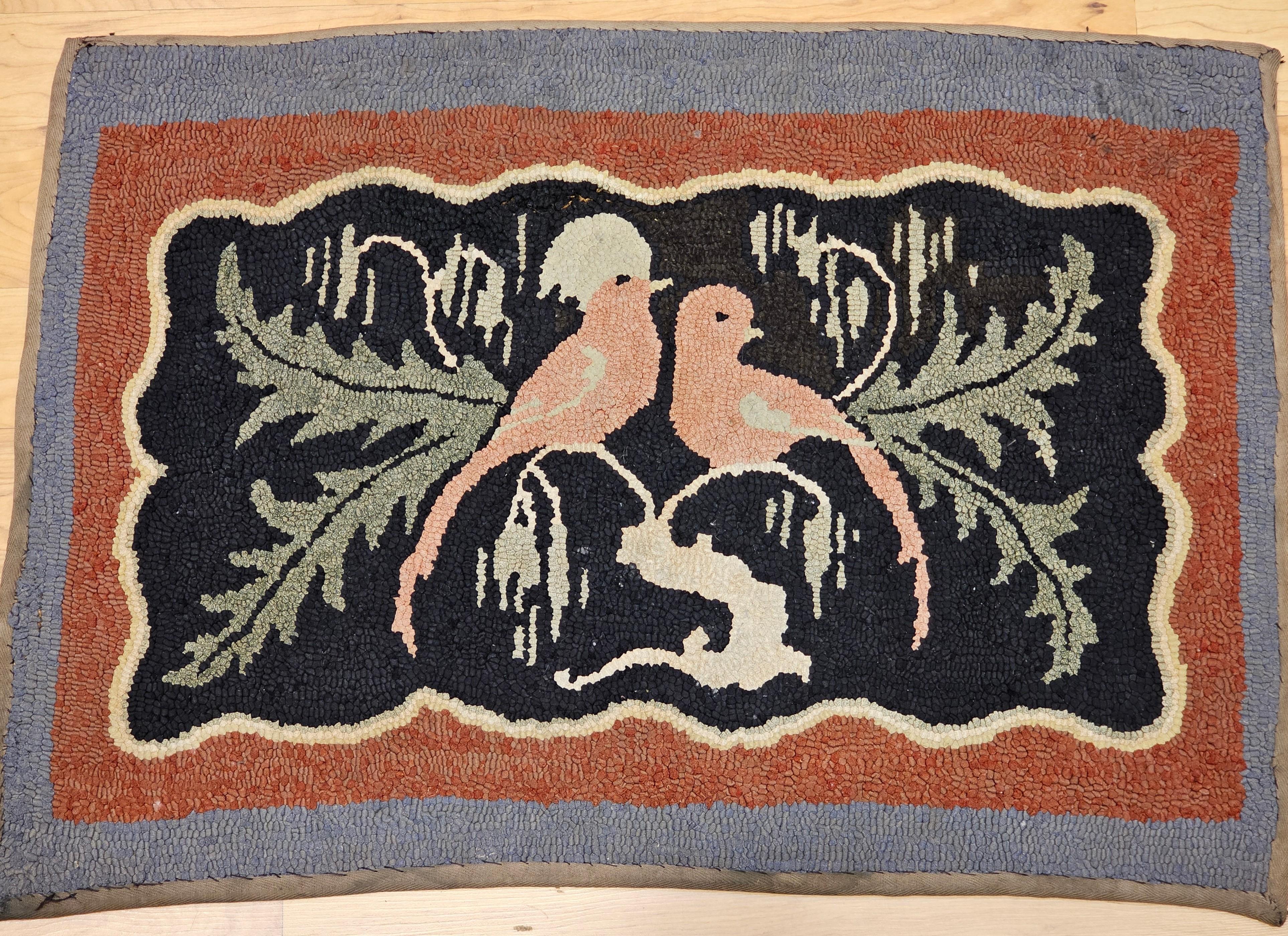  Early 20th Century hand hooked rug in a wonderful depiction of a pair of lovebirds on a tree branch.  The rug has a delightful design and colors including black, ivory, lavender pink, green, and rust red.    We are intrigued with the novelty and