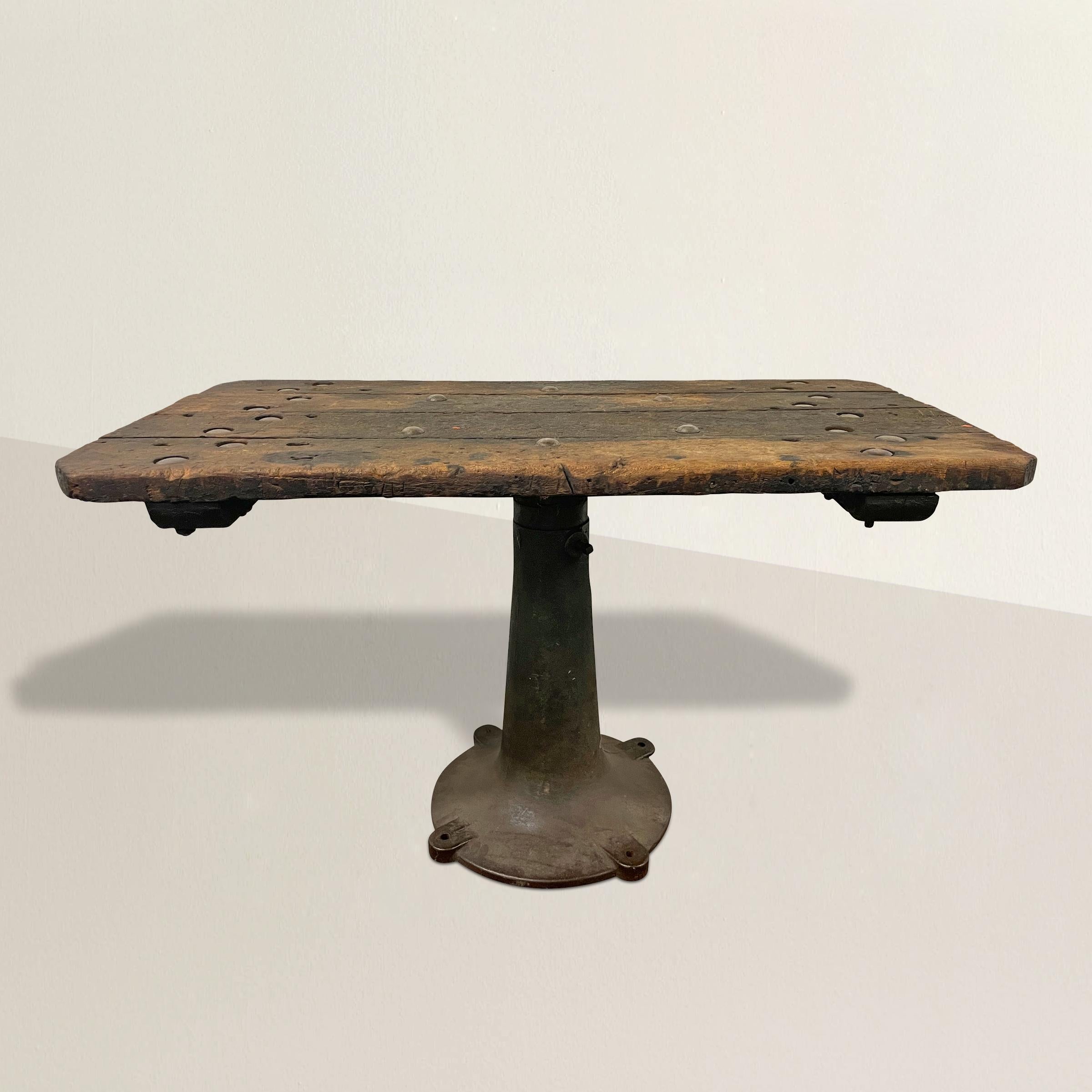 A robust and handsome early 20th century American industrial console table with a the most wonderful well-worn wood top with large steel rivets that attach the table to a heavy round iron base. Table is perfectly sized to fit in your entry, or