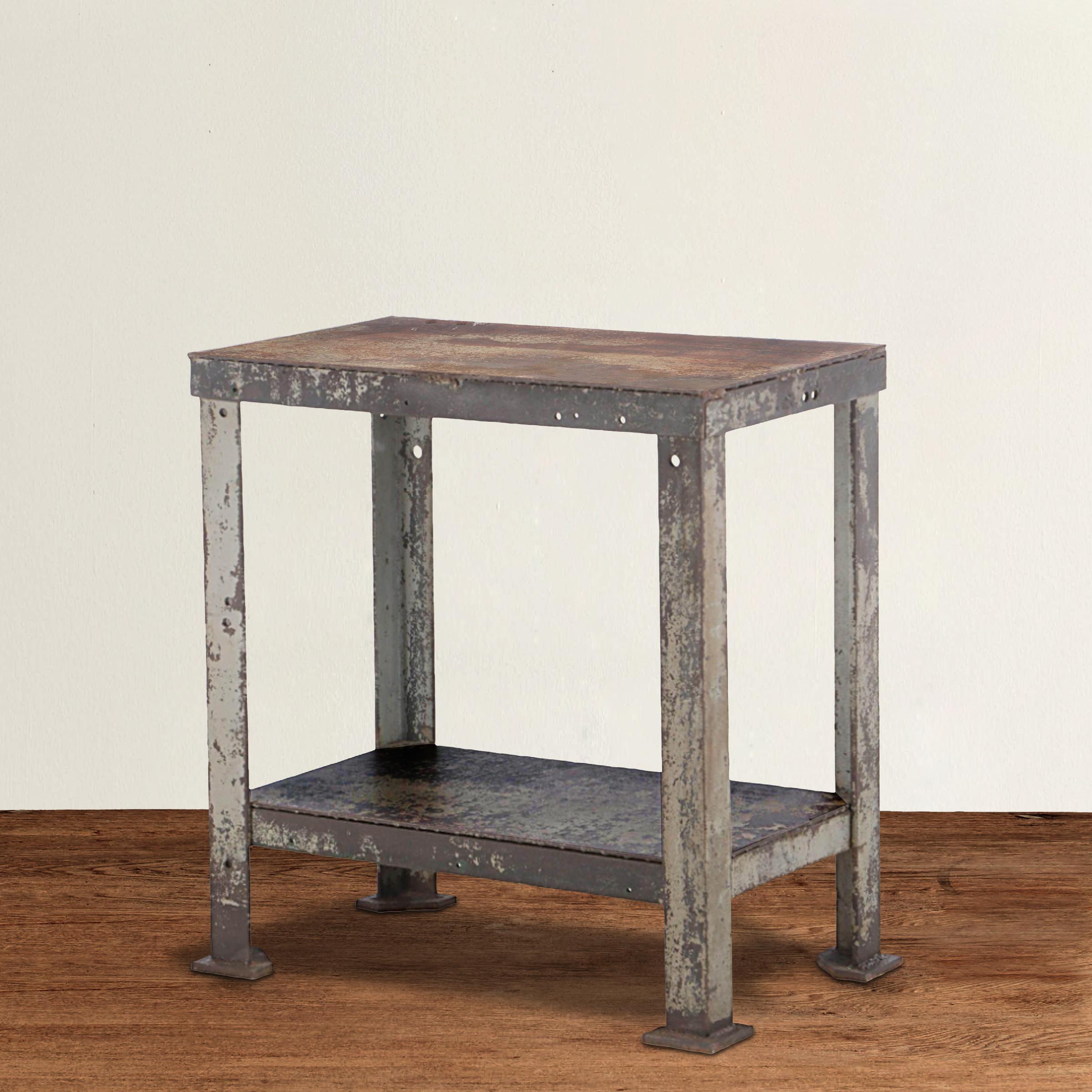 A confident and stoic early 20th century American industrial steel table with a shelf, angle-iron legs, and pad feet, and with a perfectly chippy painted and rust finish that only time can bestow. This table is the perfect console table in an entry