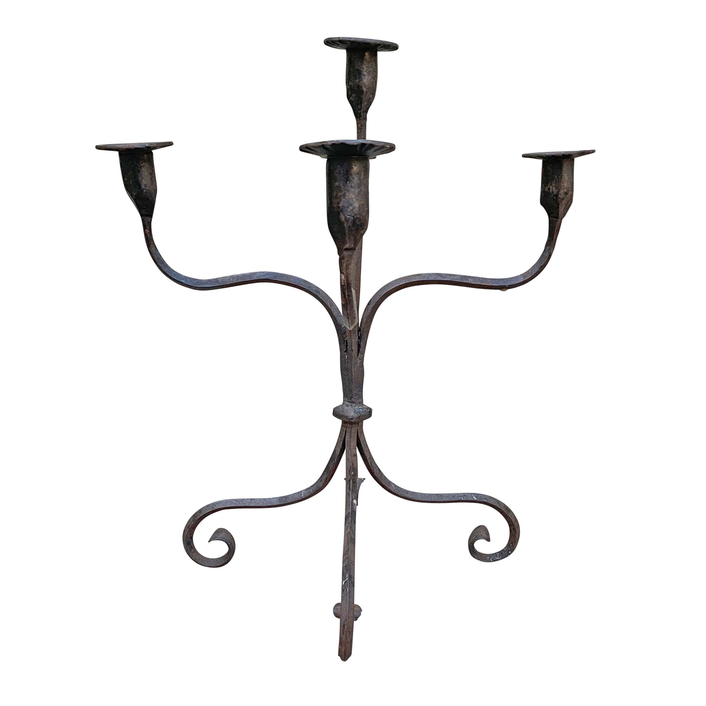 An early 20th century American hand-wrought iron four-arm five-light candelabra with a wonderfully sculptural form and long legs ending in scrolled feet.