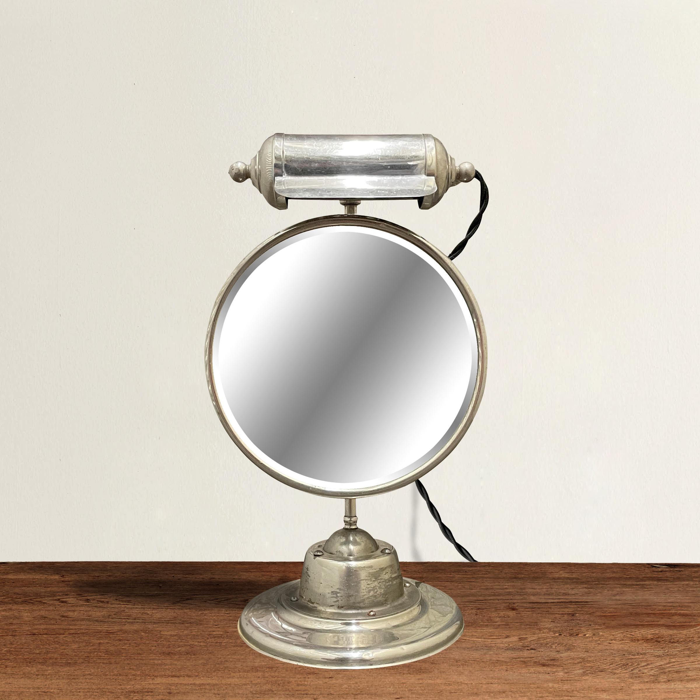 A wonderfully charming early 20th century American nickel plated shaving mirror with an adjustable light that rotates around the mirror, and mounted to another adjustable arm the allows the mirror to rotate 360 degrees. Perfect for applying makeup,