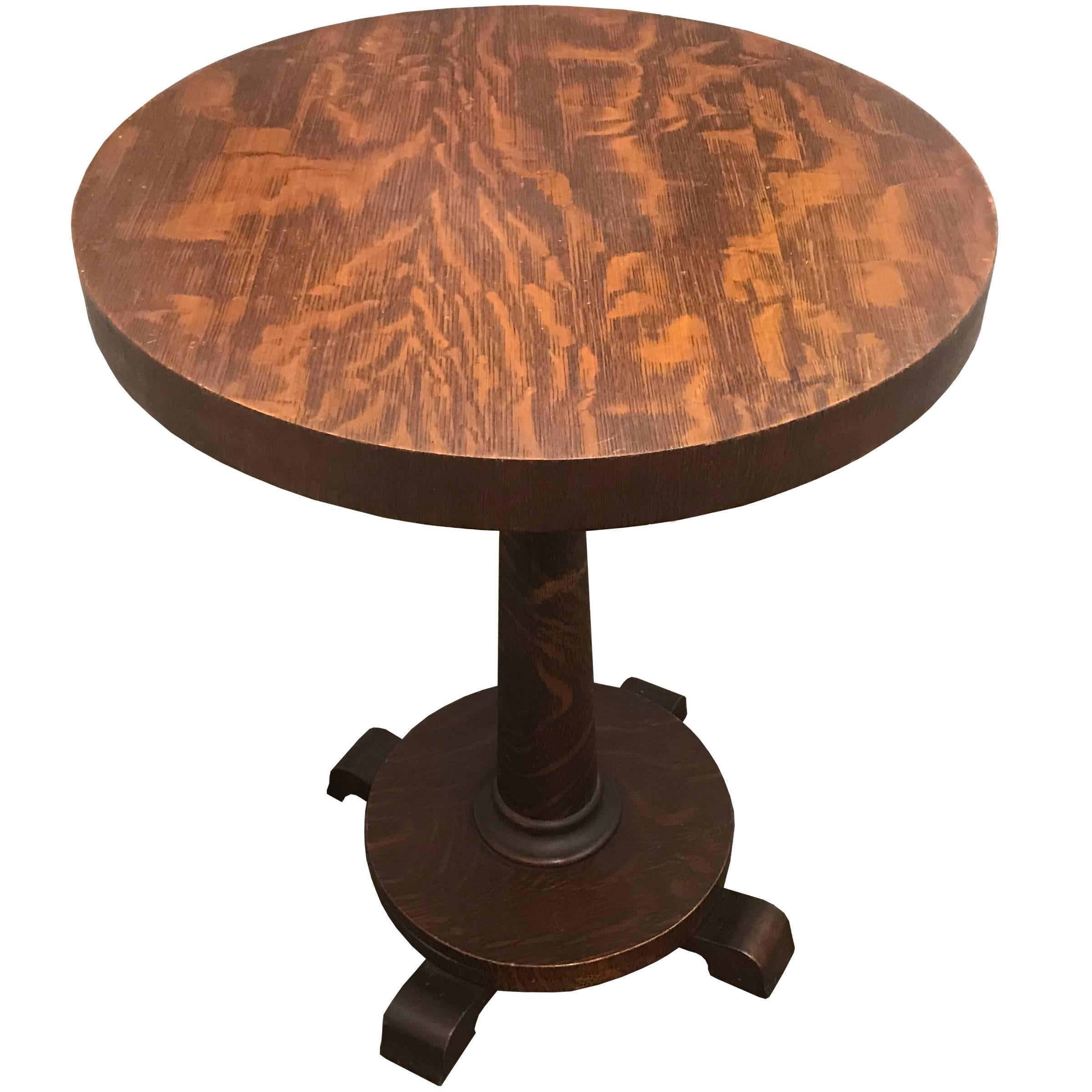 A charming early 20th century American side table with tiger oak veneer, round top, turned column, and round base with stylized pad feet. Found in Minnesota.