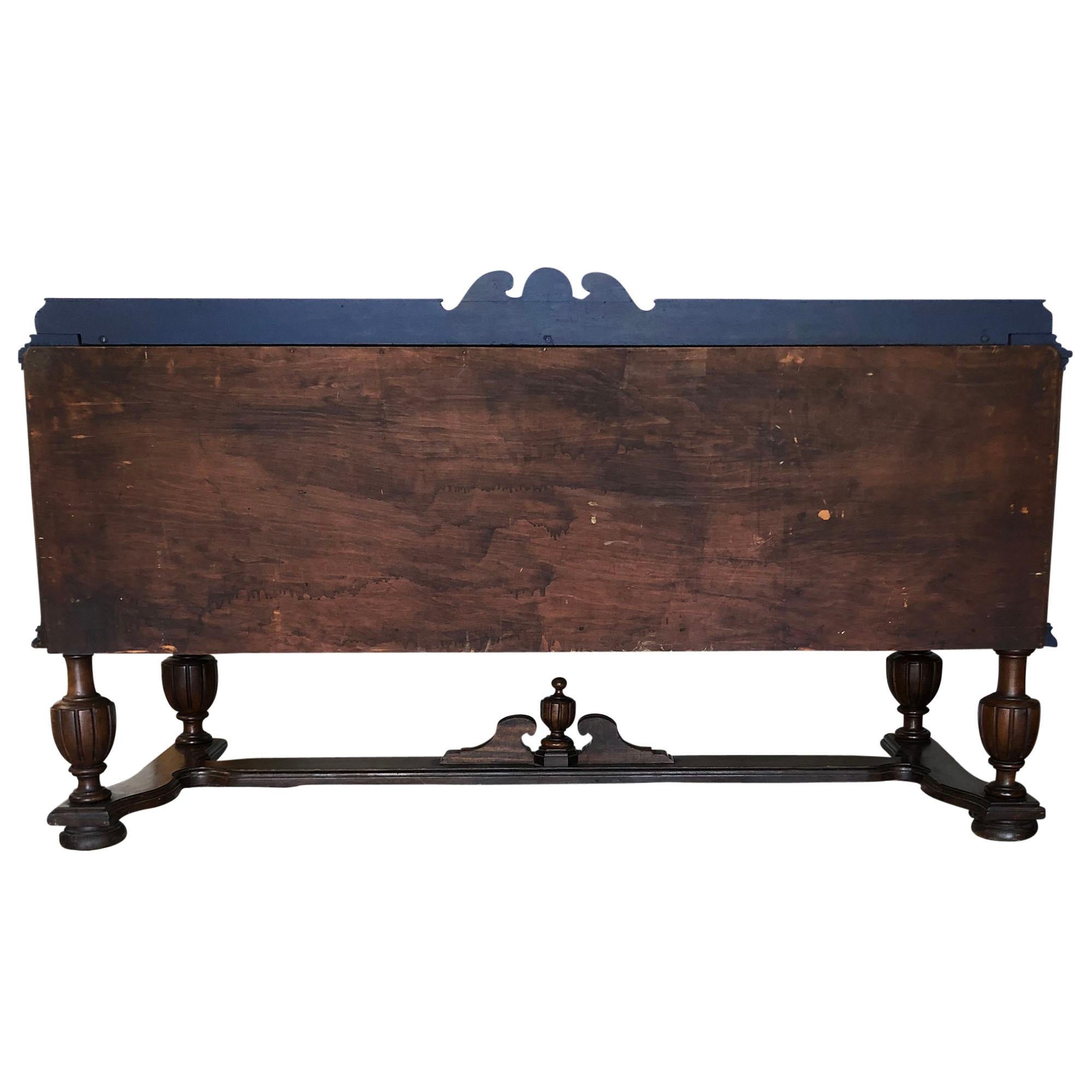 A beautiful American walnut sideboard featuring decorative veneer-work with ornate metal hardware to drawers and cabinets. It rests on carved wooden legs and is unmarked. The sideboard has been updated with navy blue accents and highlighted with a