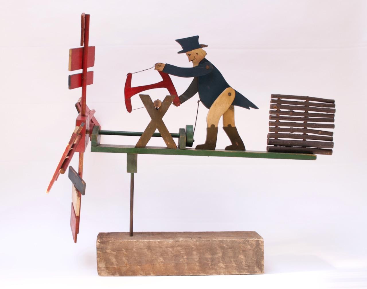 Charming whirligig depicting a figure resembling Uncle Sam sawing a log mounted to a wooden base. Hand carved, painted, and assembled with applied facial details. When manually turned, the propeller activates the woodman's 'sawing' motion.
This