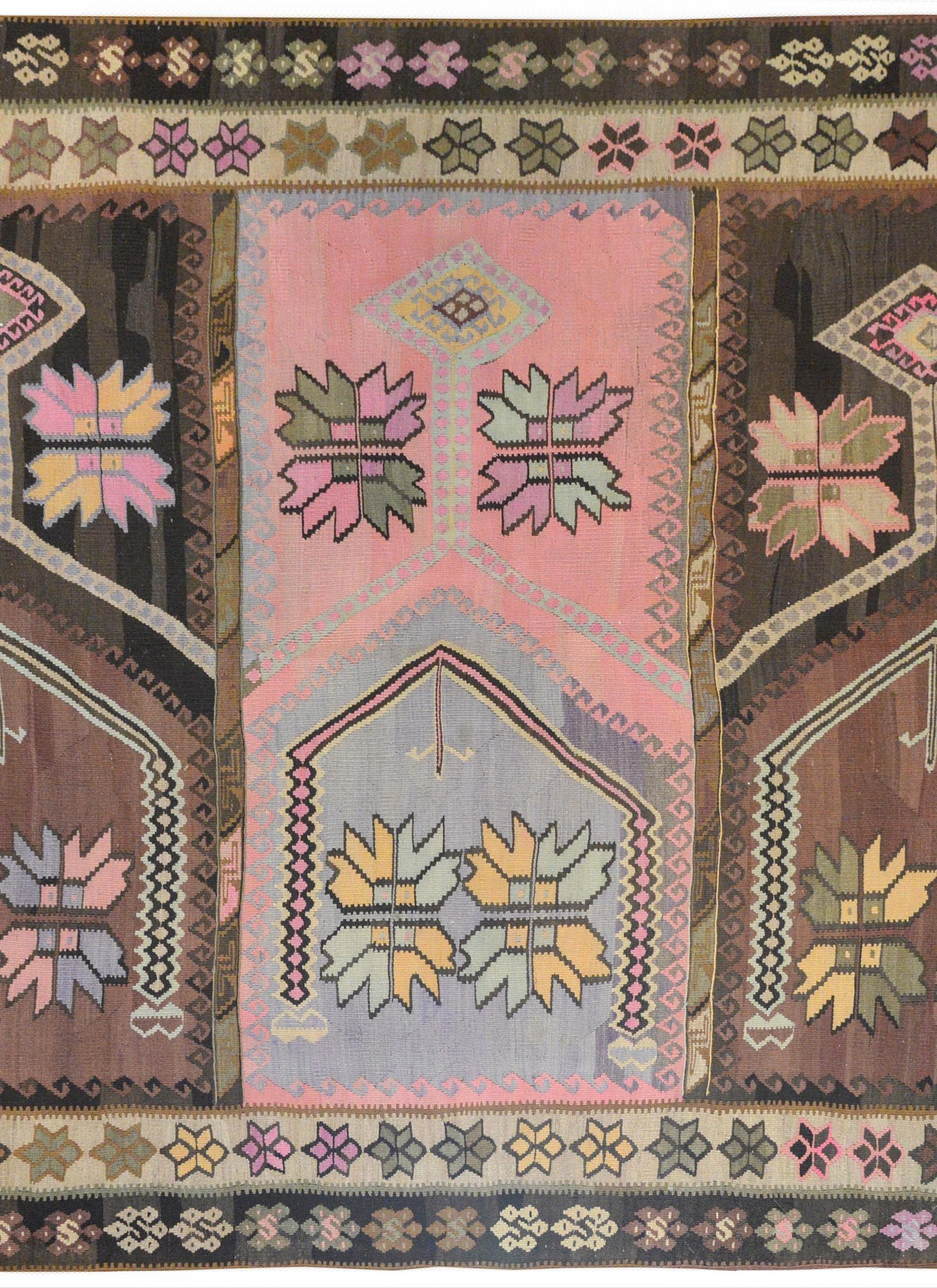 An early 20th century Turkish Anatolian Kilim rug with three central segmented panels, each with stylized flowers and surrounded by geometric wave patterns. The border is composed of two distinct stylized floral patterned stripes.