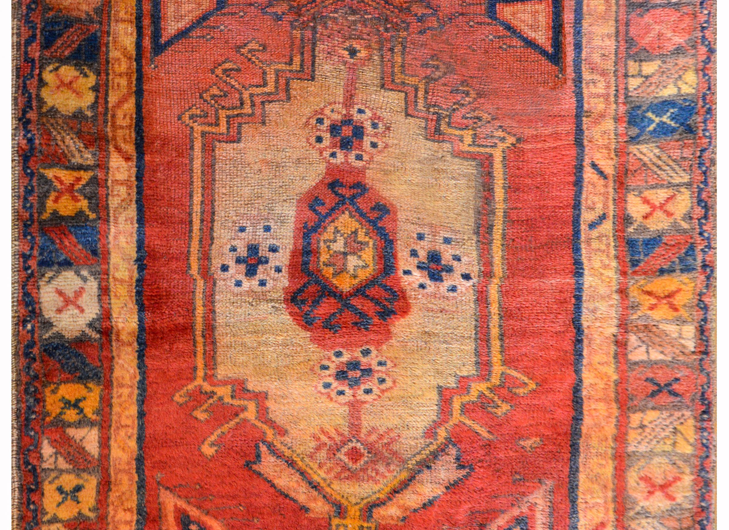 A wonderful early 20th century Turkish Anatolian rug with a large central medallion woven in indigo, cream, orange, and crimson, on a rich crimson background surrounded by multiple stylized floral patterned stripes.