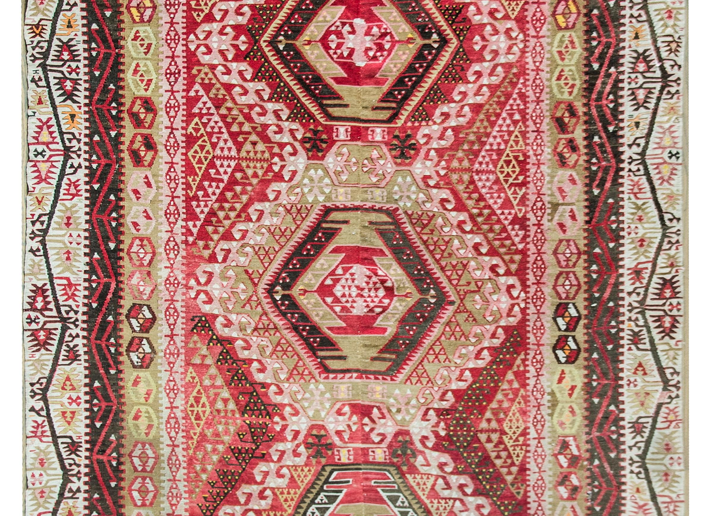 A wonderful early 20th century Anatolian Turkish rug with five large diamond medallions flanked by an incredible field of stylized flowers and vines all woven in beautiful pinks, crimsons, whites, and browns. The border is equally as stunning with