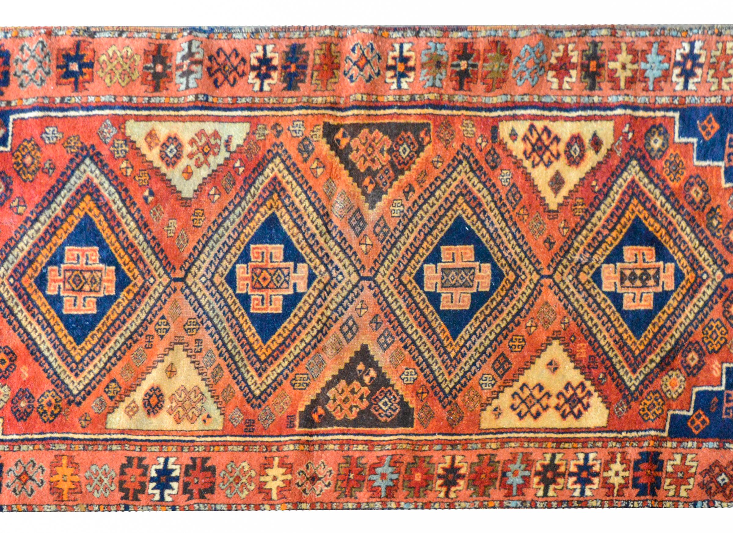 A wonderful and bold early 20th century Anatolian Turkish runner with four large diamond medallions, each woven with a geometric pattern with alternating colored stripes and set against a field of stylized flowers against a crimson field. The border
