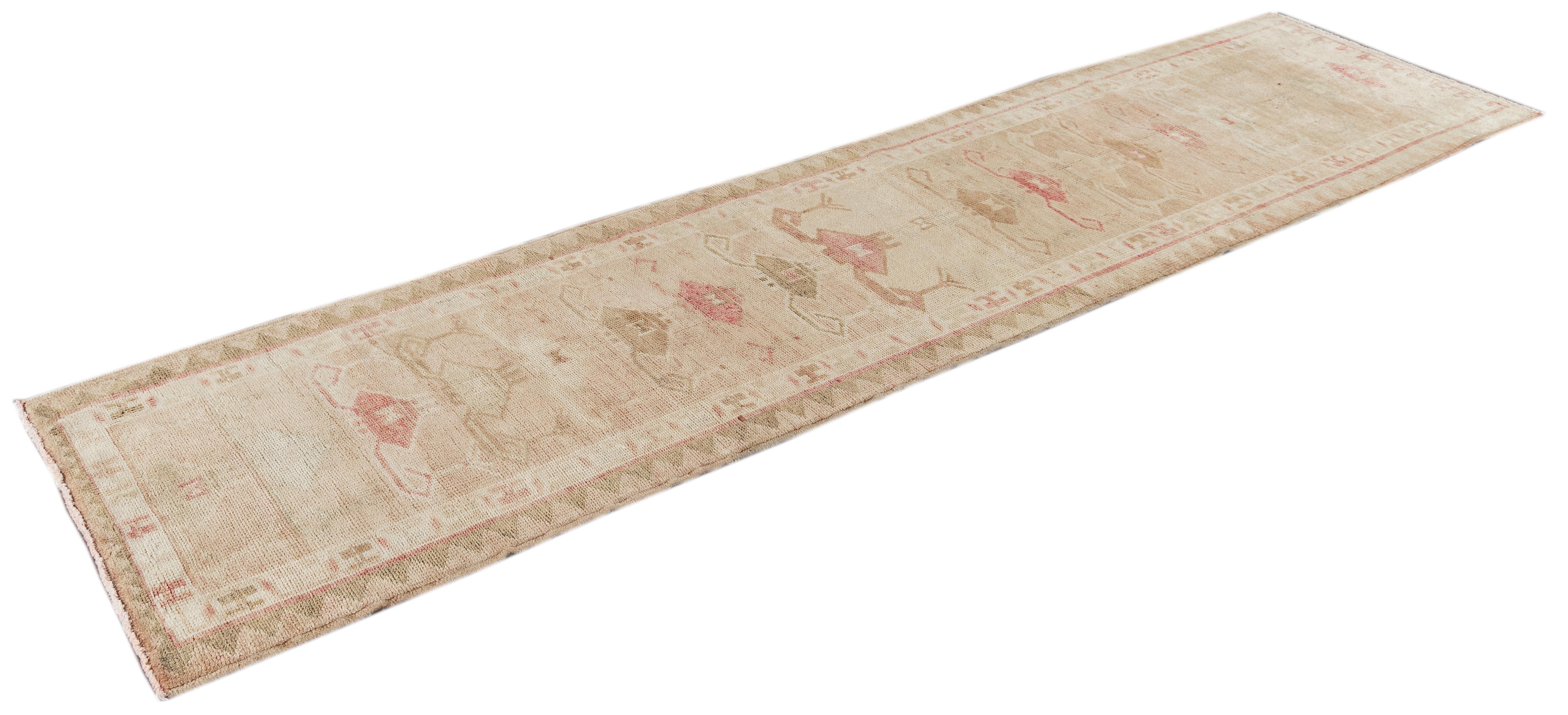 Beautiful Anatolian Village Turkish Runner rug, hand knotted with a tan field, ivory, light brown and pink accents in all-over geometric medallion design.

 This rug measures 2' 10