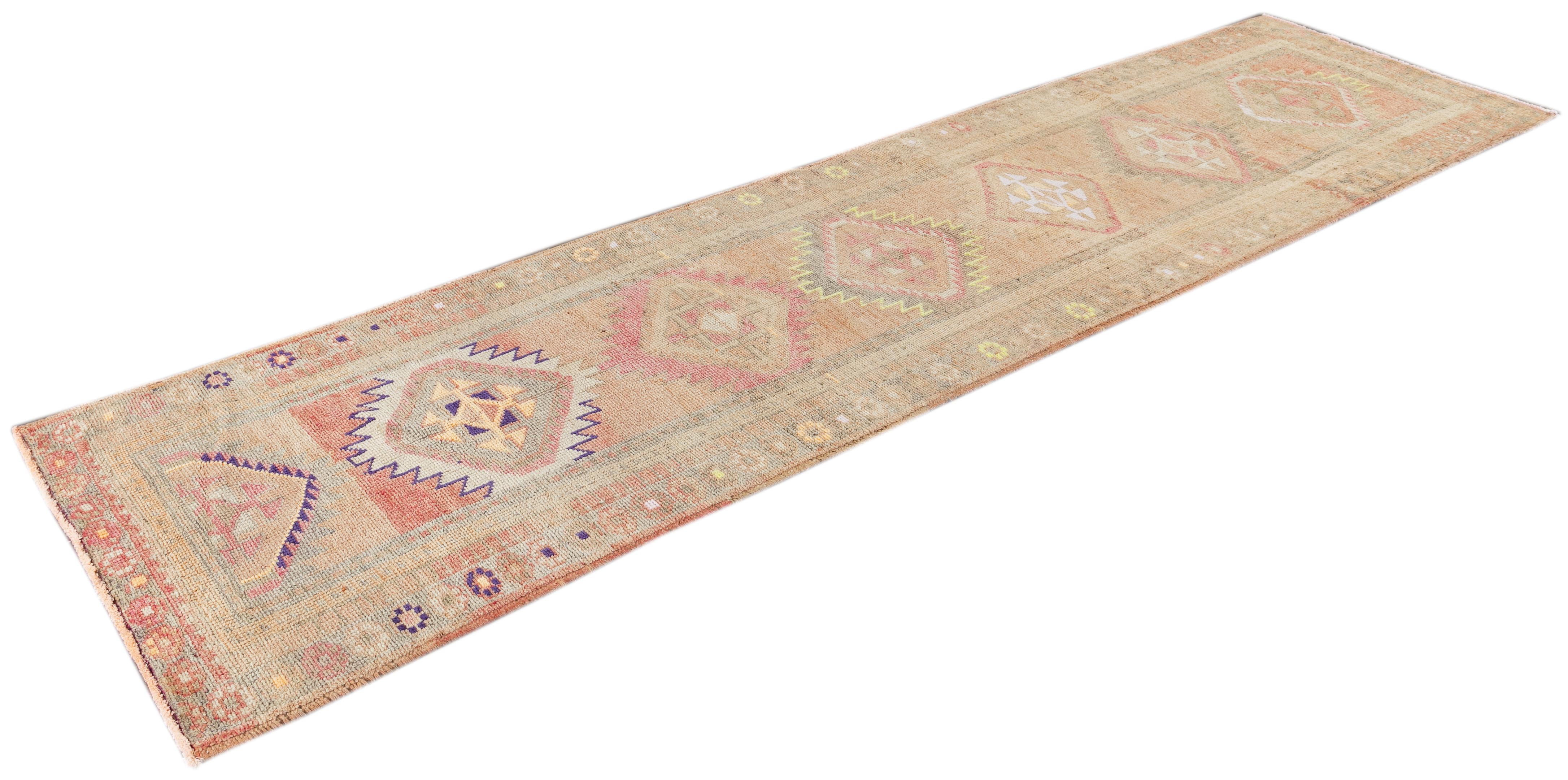 Beautiful Anatolian Village runner rug, hand knotted wool with a tan field, ivory, pink and gray accents with an allover geometric medallion design.

This rug measures 3' 2