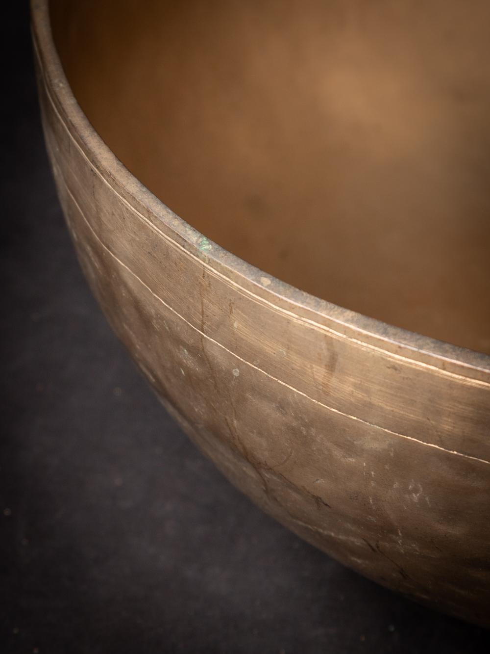 This antique bronze Nepali Singing bowl originates from Nepal and dates back to the early 20th century. Crafted from bronze, it showcases the rich cultural heritage of Nepal. The bowl stands at a height of 16.9 cm with a diameter of 42.2 cm, making
