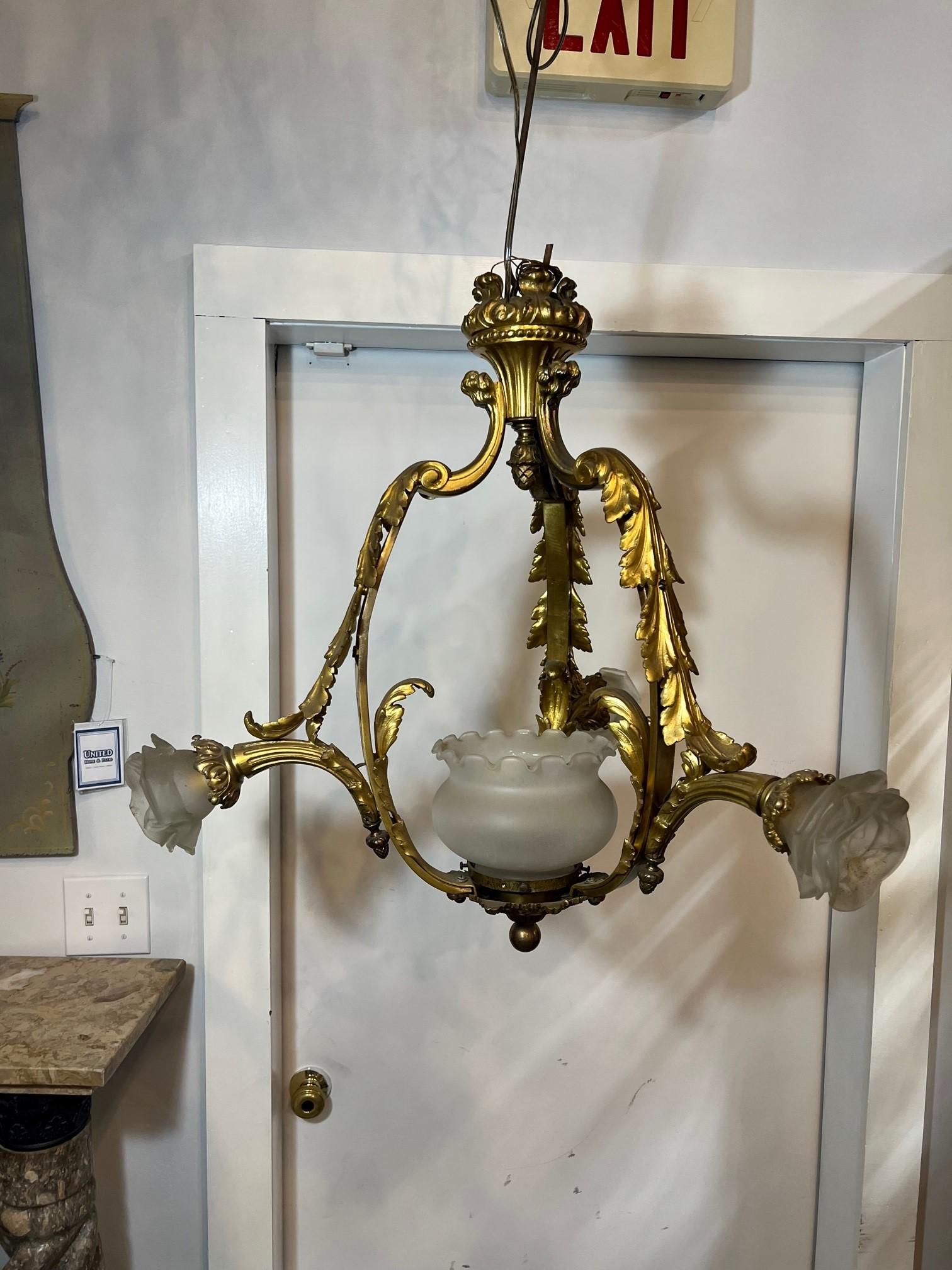 Early 20th century ( maybe earlier ) bronze three arm chandelier from Paris France. The bronze filigree and acanthus on the arms look amazing as shown in the photos. The chandelier has three glass shades and one glass globe in the center which have
