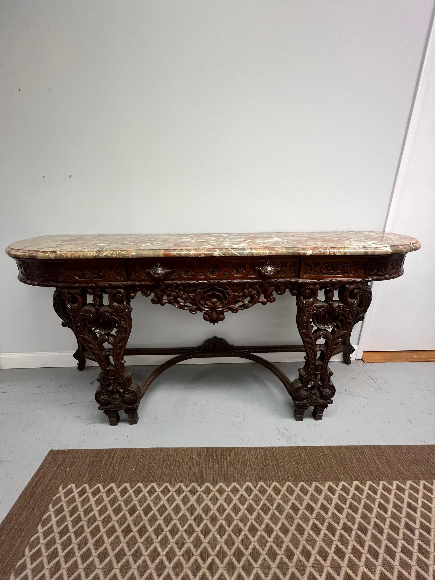 Questo bellissimo server con piano in marmo intagliato e cassetto singolo ha un piano in marmo unico con molti colori. Un tempo questo era uno dei tanti pezzi di un magnifico set da sala da pranzo. L'intaglio di questo server è incredibile, come