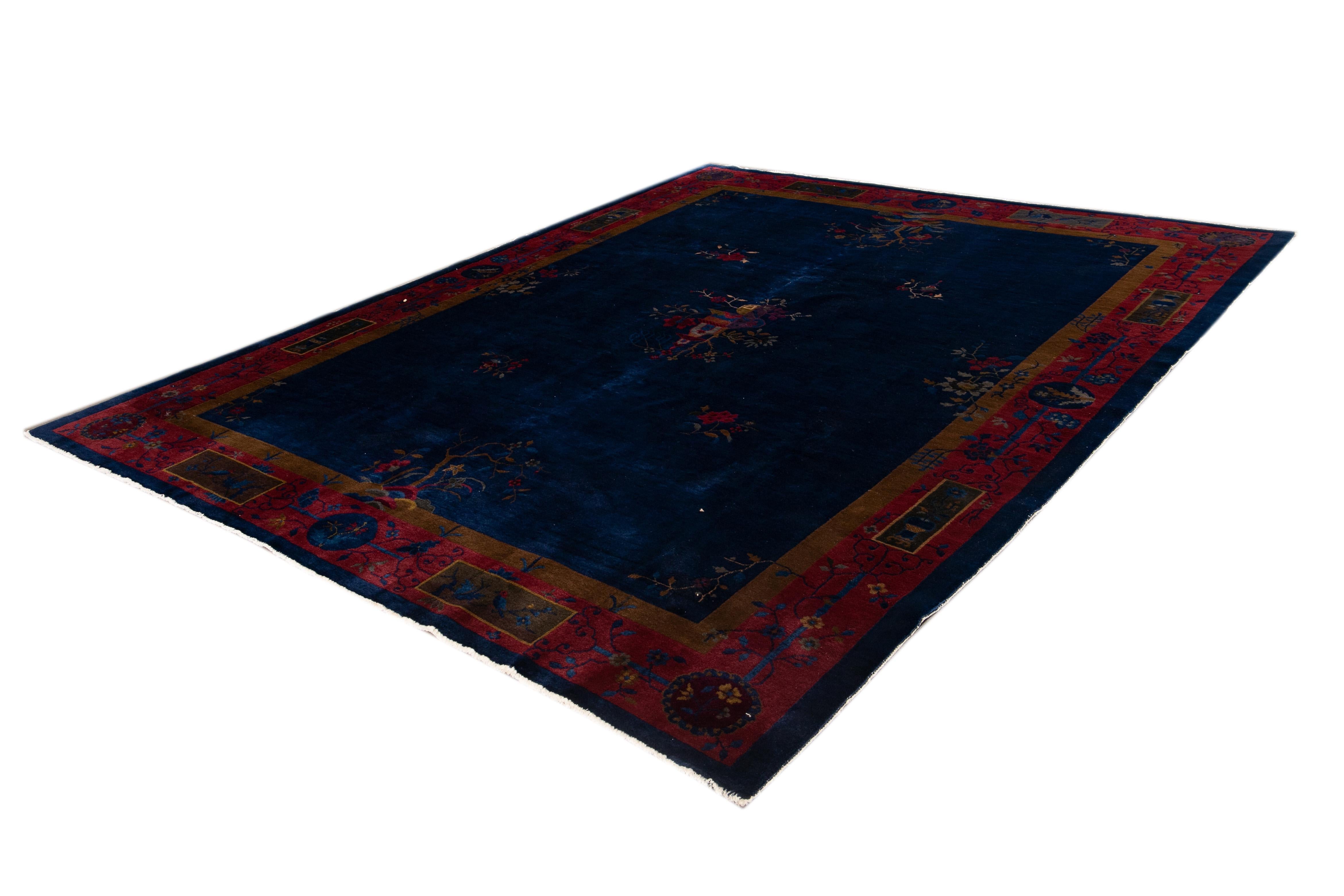 Beautiful vintage Chinese Art Deco hand-knotted wool rug with a navy blue field and red border with multicolored accents and all-over floral design.

This rug measures 9' 0