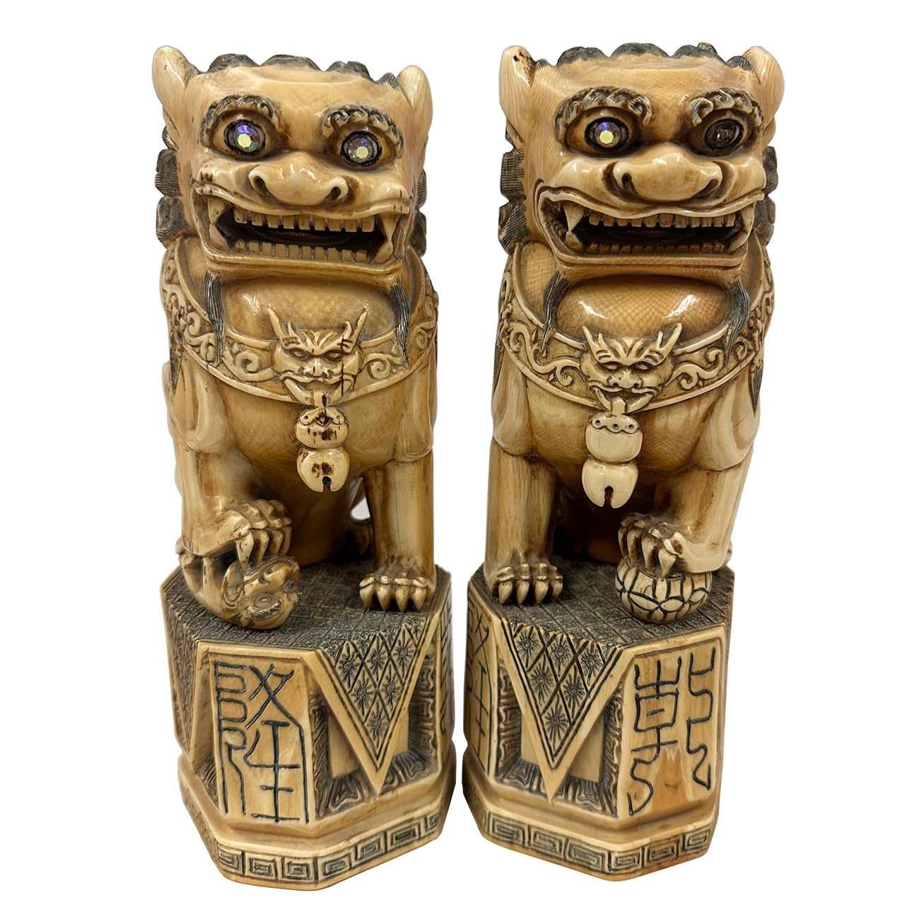 Dans cette paire assortie de lions/chiens de foire mâle et femelle avec crinière bouclée et yeux globuleux, la femelle tenant son petit sous une patte ; le mâle avec une balle brodée. Chacun porte un collier orné de  Le tout est orné de glands et