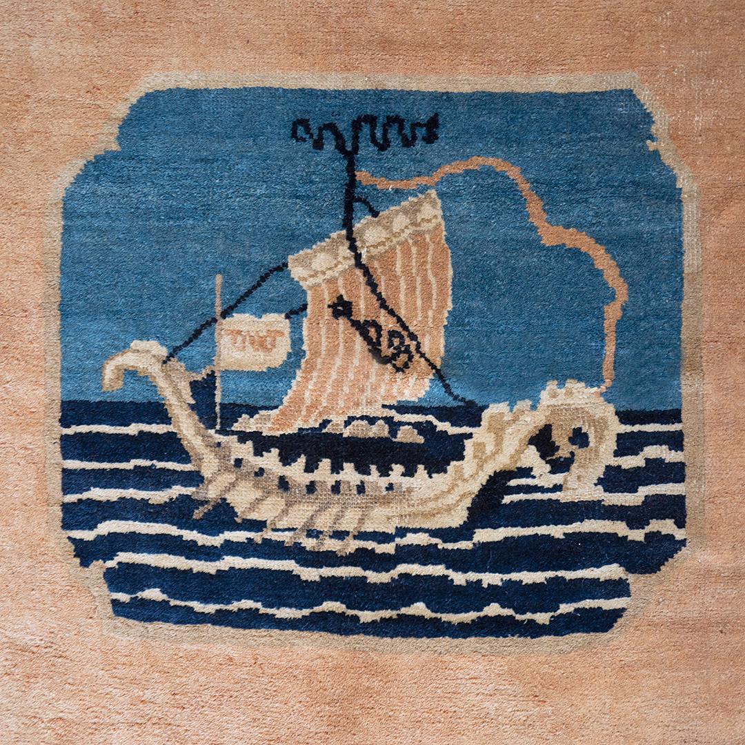 This traditional hand-woven Chinese rug has a shaded coral open field with pictorial sailboat panel opposed by a single elegant seagull, in a deep indigo border adorned by two sapphire drakes.