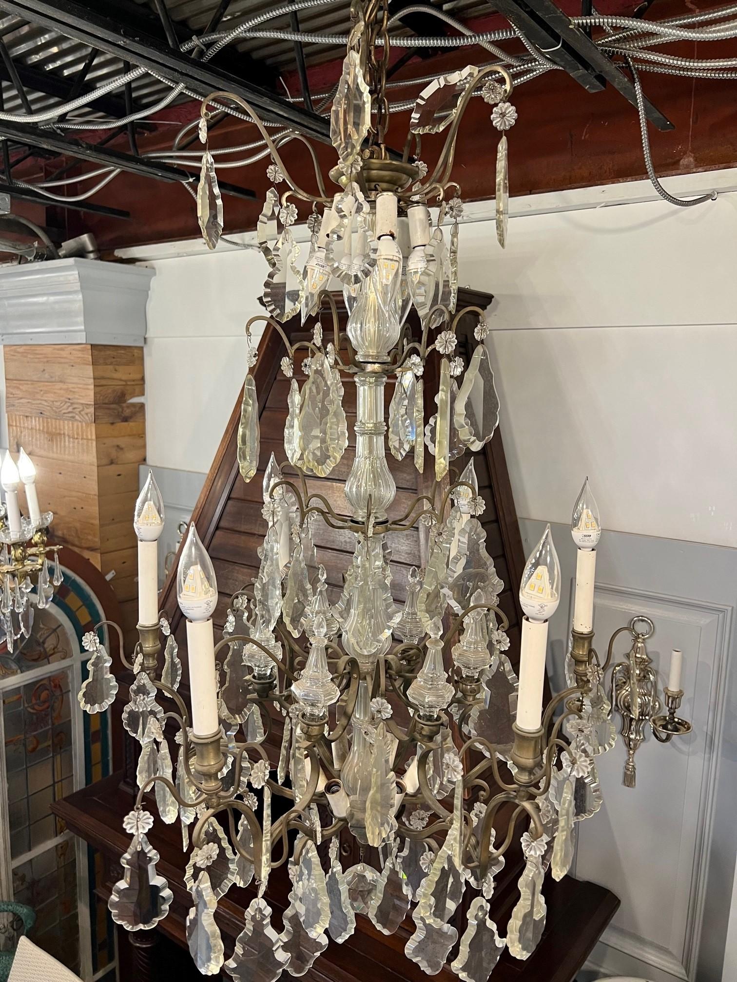 Beautiful antique crystal chandelier made in France. Delicate brass scrollwork is embellished with many different shaped cut crystals and elaborate crystal finals. The chandelier has six arms with candelabra lights and also six lights above and