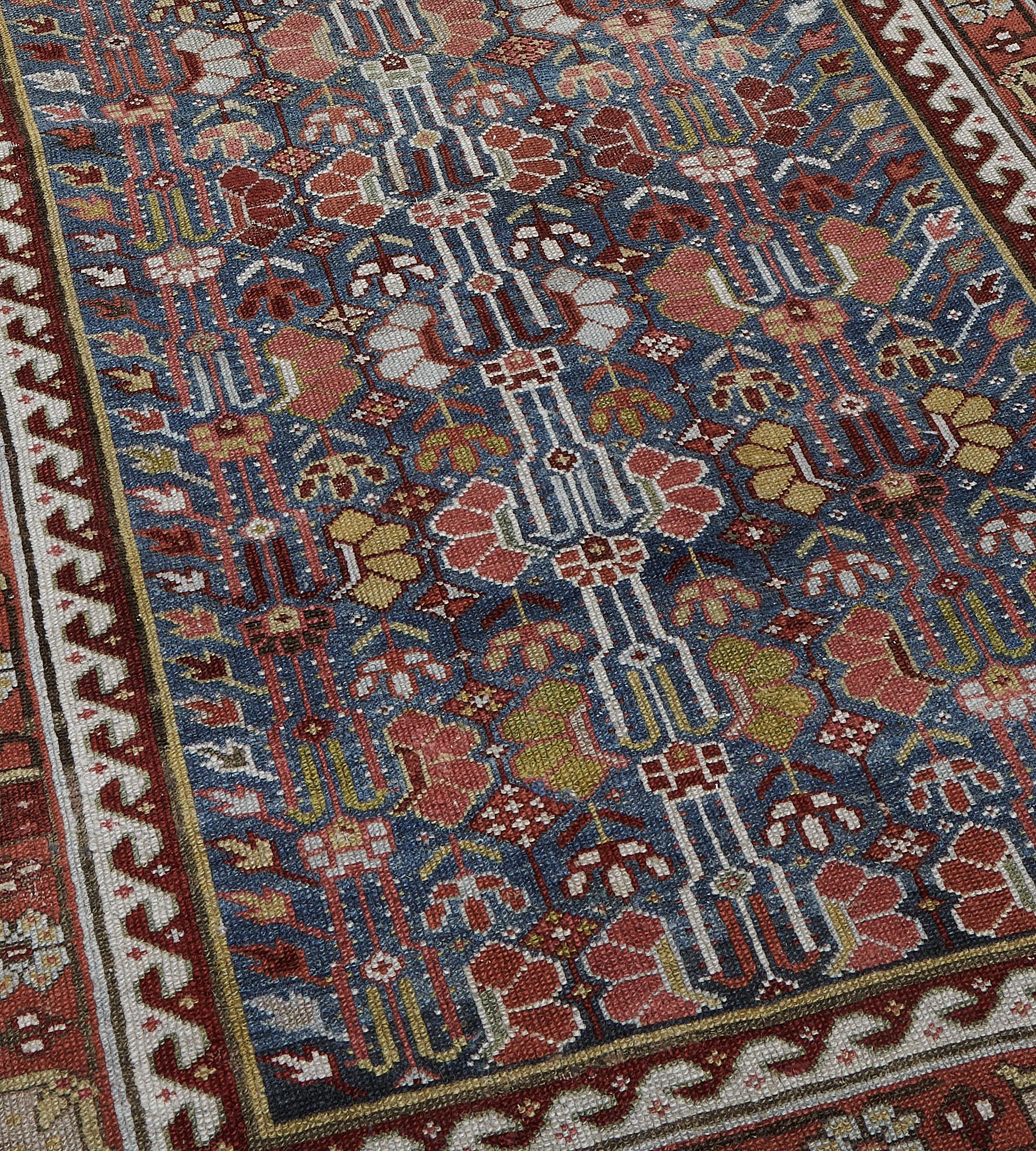 Dieser antike persische Läufer hat ein schattiertes meerblaues Feld mit einem Gesamtmuster aus drei vertikalen Säulen mit polychromen ziegelroten, elfenbeinfarbenen und pistaziengrünen Blumenspritzern, die von einer eckigen Ranke ausgehen und von