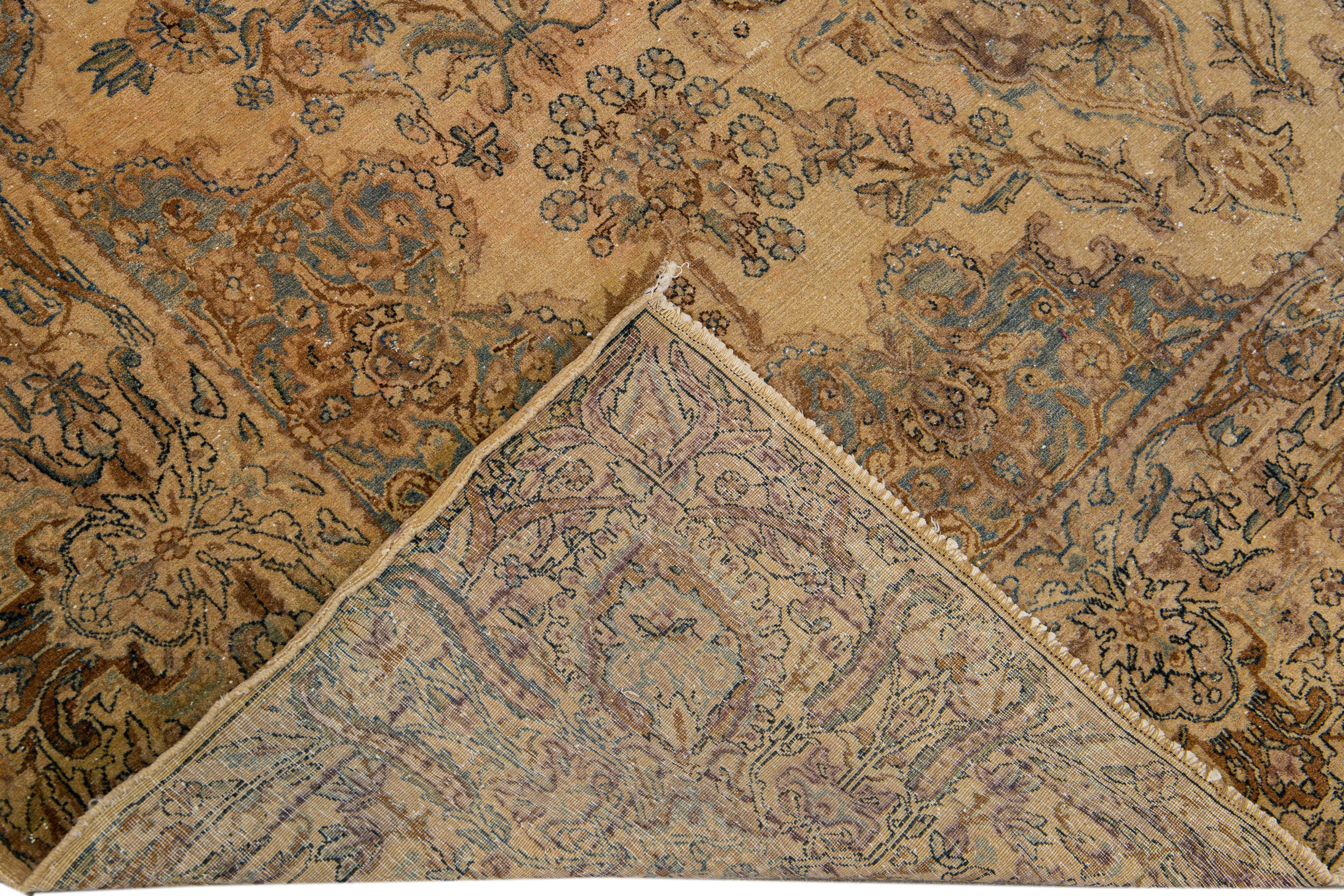 Beautiful antique Kerman hand-knotted wool rug with a tan field. This Persian rug has brown and blue accents in a gorgeous floral center medallion design.

This rug measures 7' x 10' 2