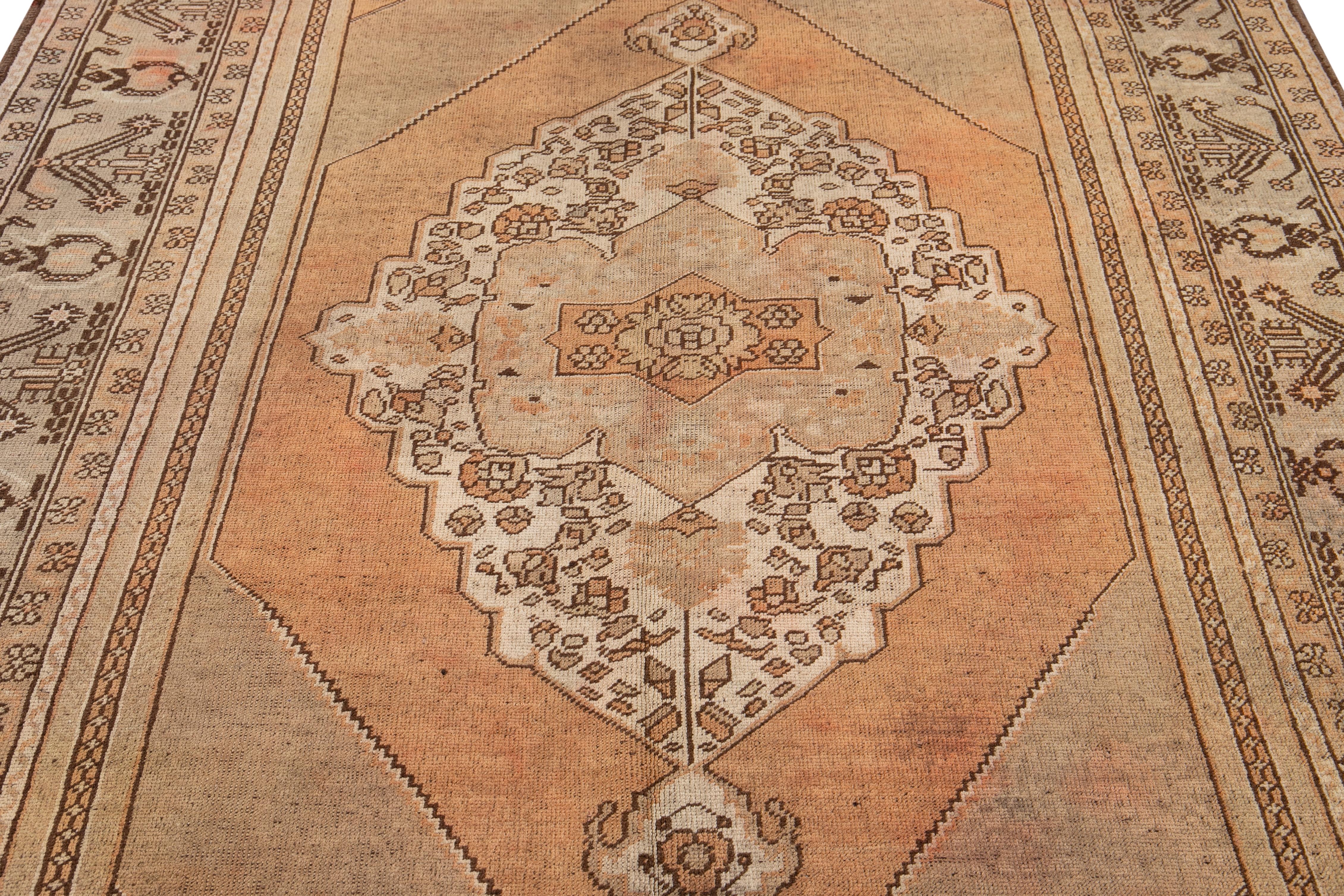 Beautiful Antique Khotan hand-knotted wool with a brown and orange rust color field. This piece has a designed frame and beige accents in a center medallion design.

This rug measures 6' 5