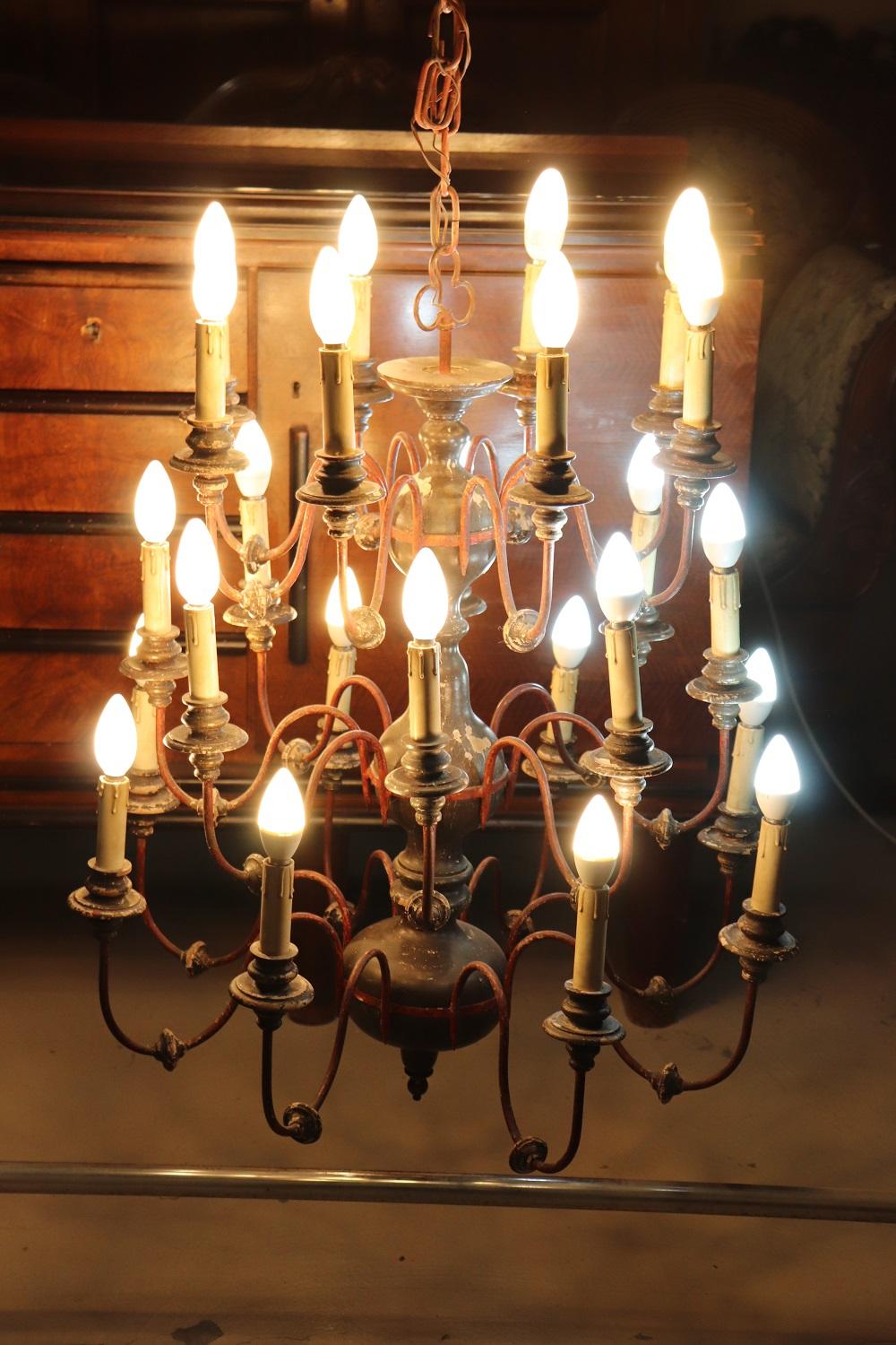 Lovely early 20th century antique large chandelier with twenty four bulbs arranged over three floors. This majestic antique chandelier is made of lacquered wood with dark red lacquered iron arms. It is a large chandelier perfect to be placed in a