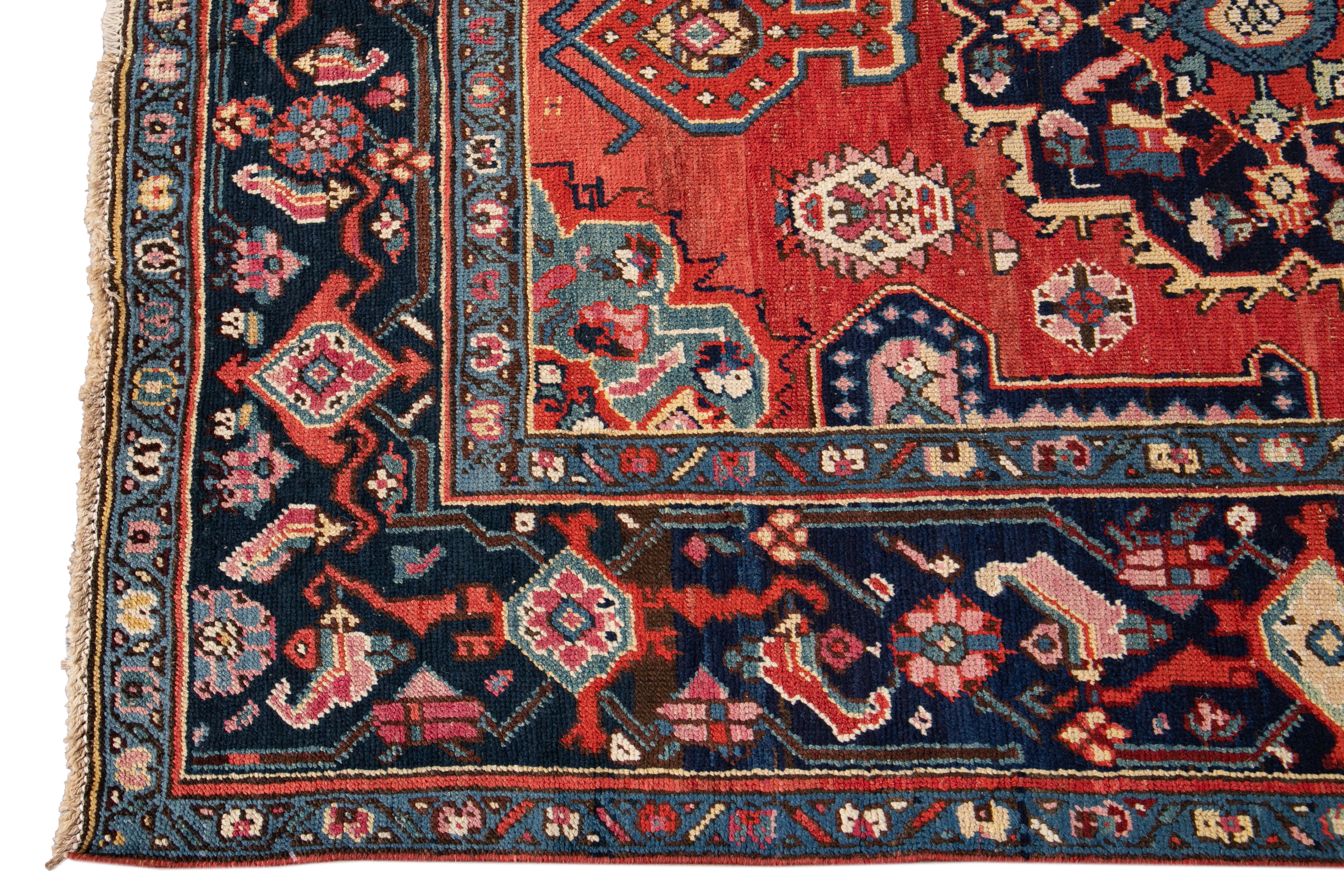 Hand knotted rug with a floral and medallion design on a red field with blue borders. 

This rug has magnificent detailing and would be perfect for any room. Measures: 5.1