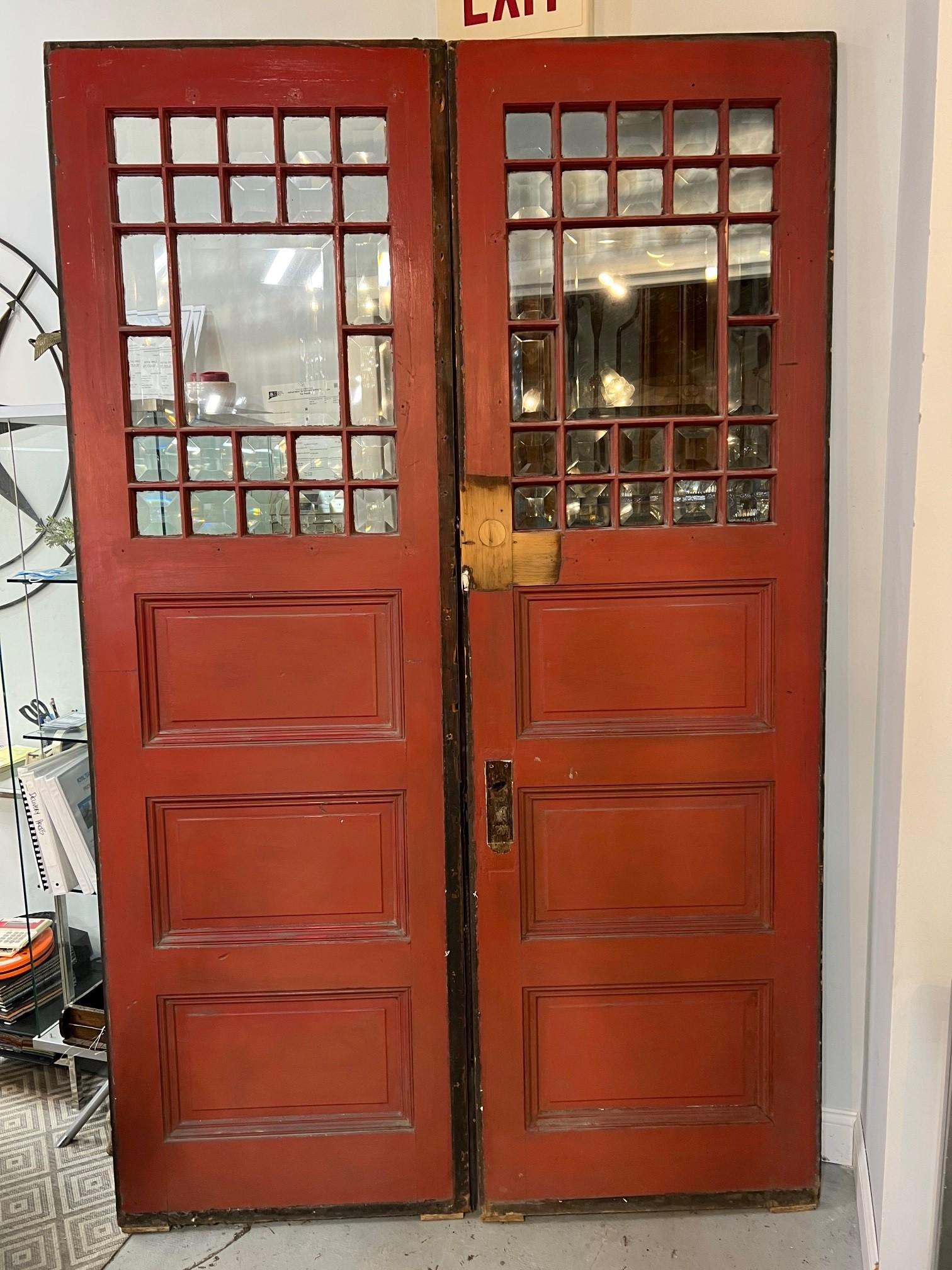 Early 20th century pair of doors with beveled glass panels from a Western Pennsylvania estate. The 24 small beveled panels around a larger panel make the doors very unique and look fantastic with the sun or any light shining on the beveled glass
