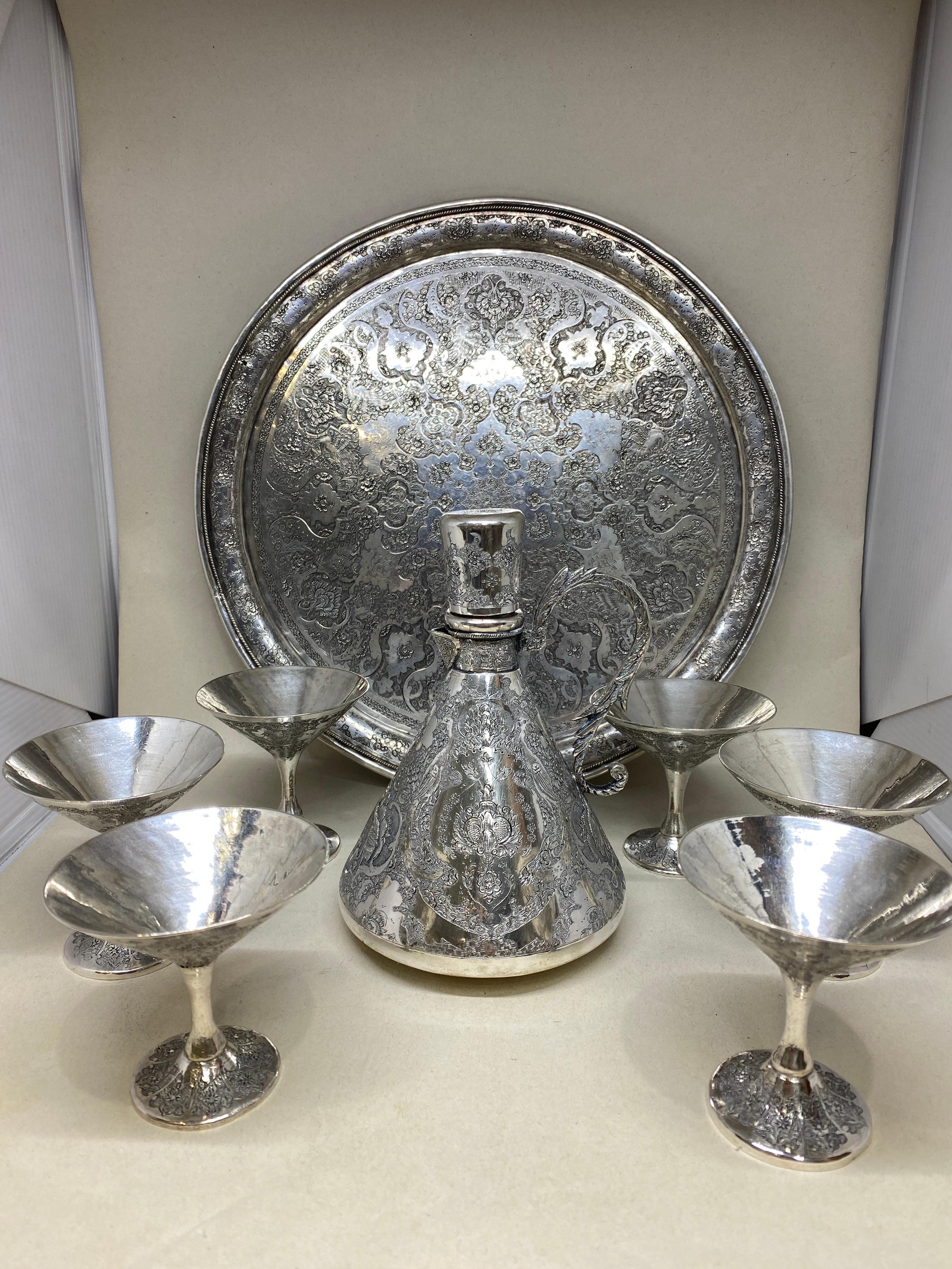 Up for your consideration is this fine Persian Islamic Silver drinking set, comprising of a decanter and six goblets and tray.

Each piece profusely hand engraved and chased with typically Persian arabesque, foliate and bird decoration, the decanter