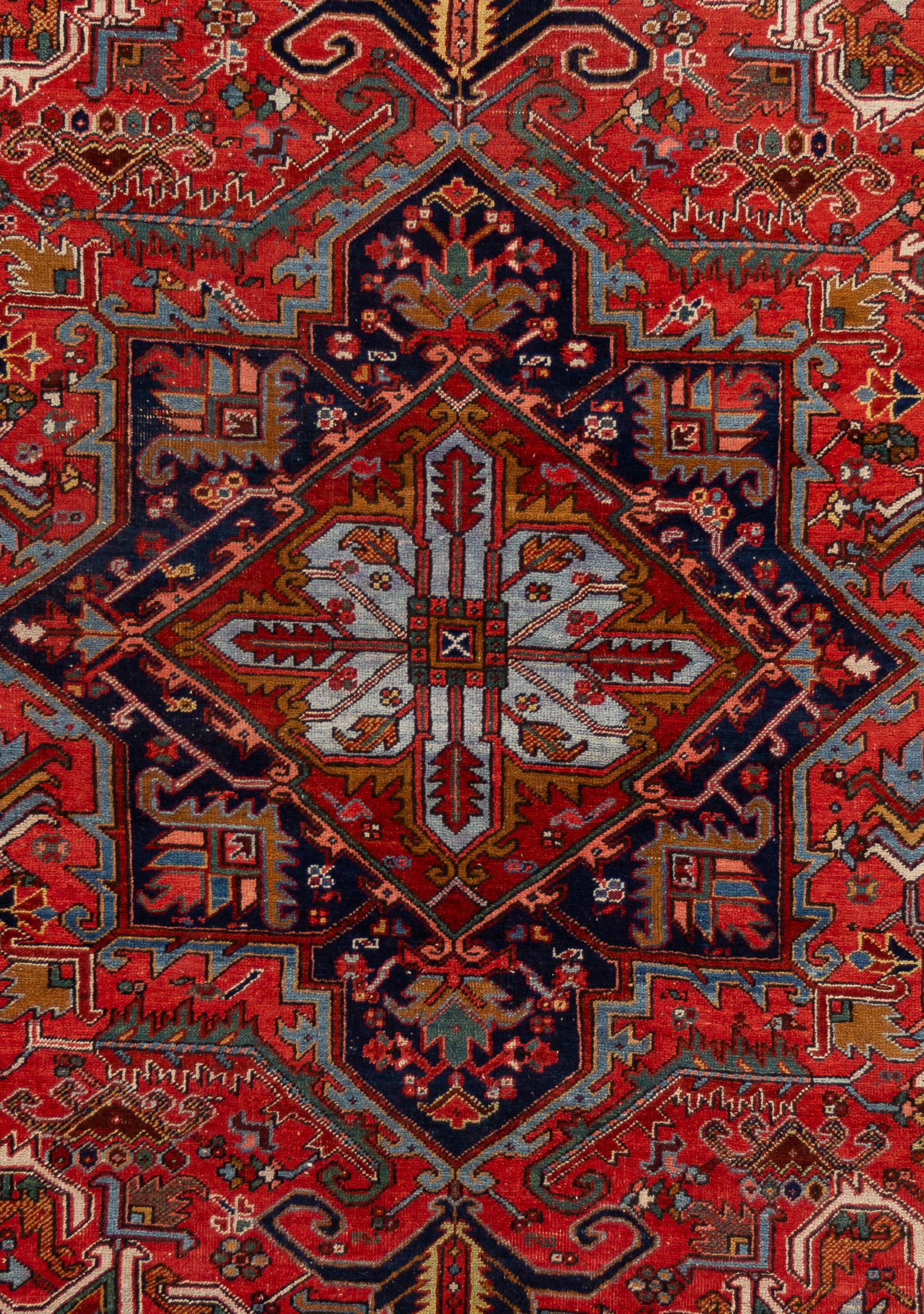 Beautiful Vintage Persian Heriz rug, with a red field and blue accents lined by a black border with a medallion design in the center. 

This rug measures 7' 6