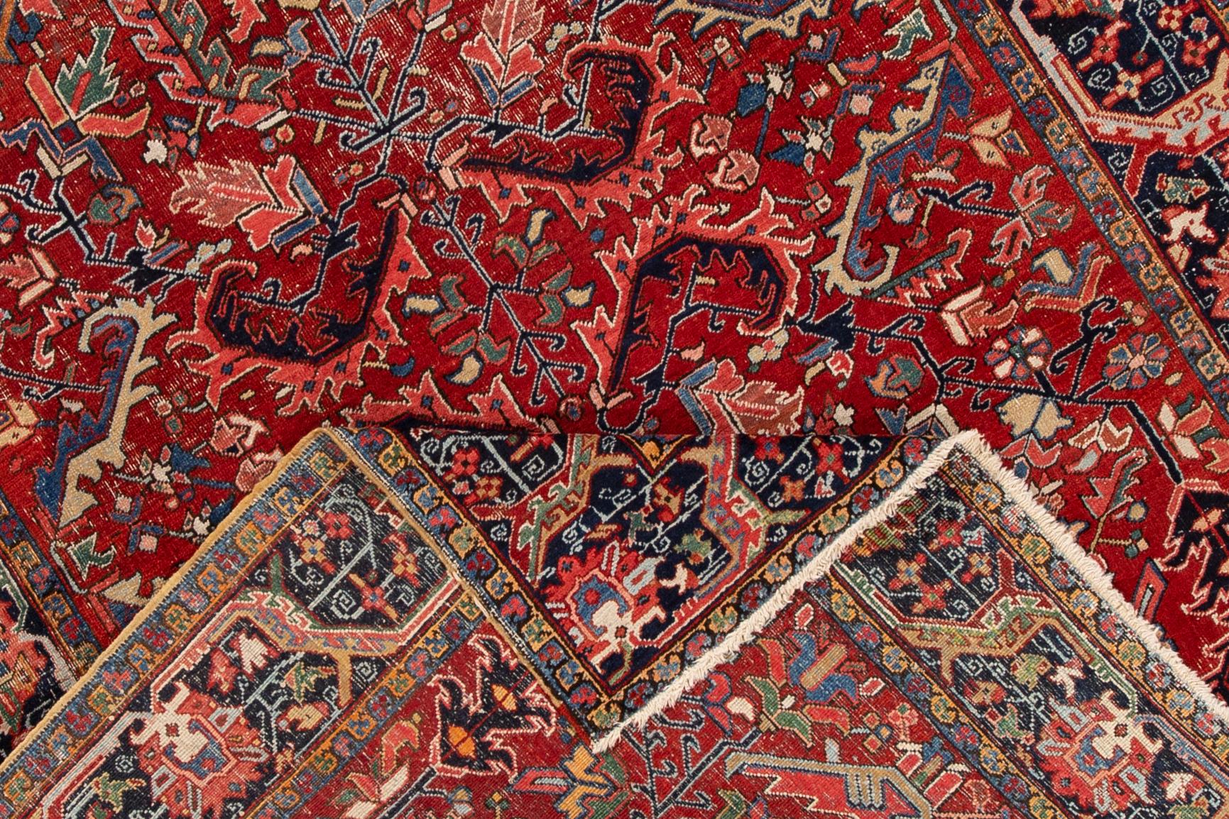 Beautiful hand knotted antique Heriz wool rug with a red field. This rug has a black border around an all-over multicolored medallion design, circa 1920.

This rug measures: 7'0