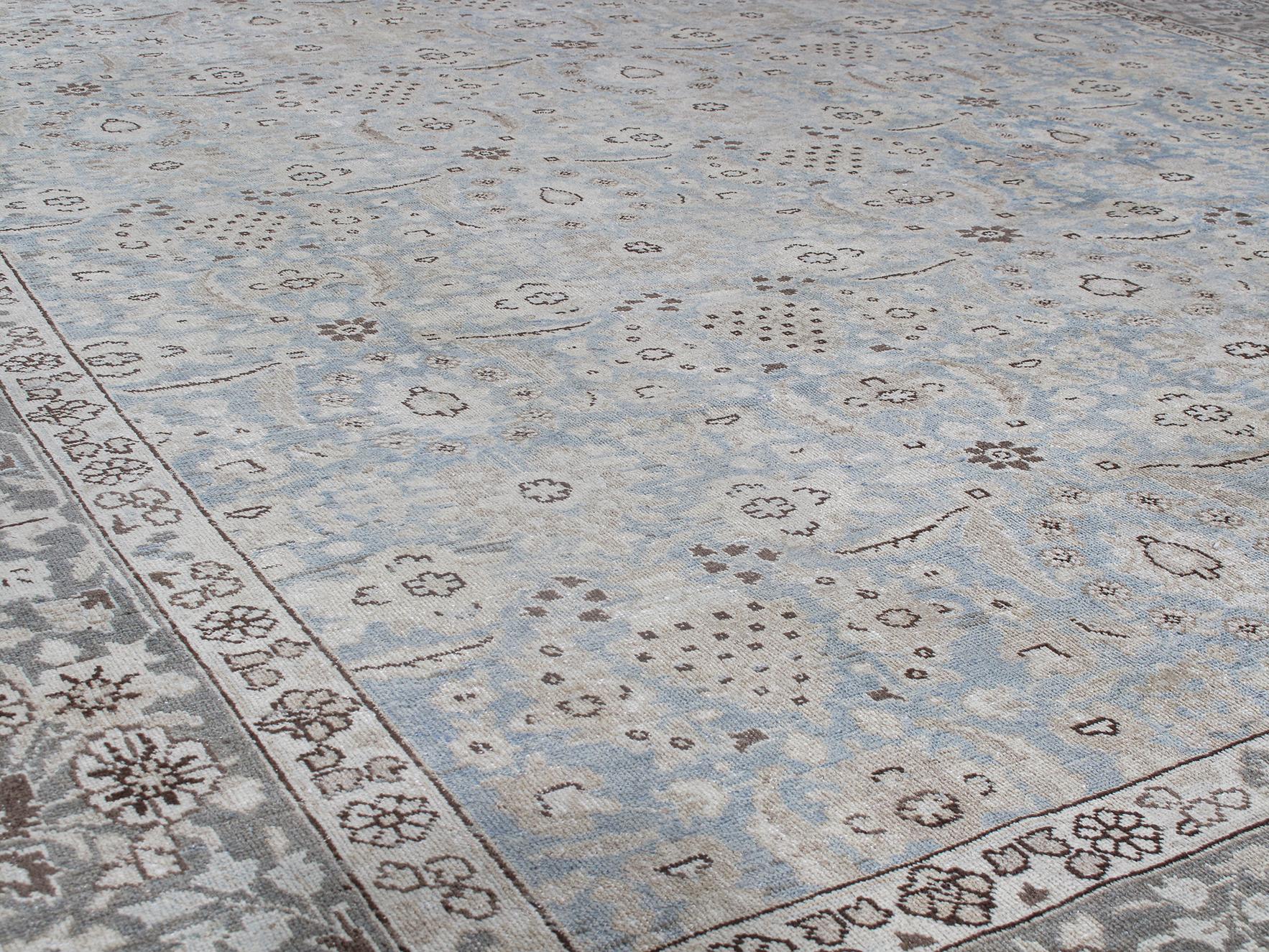 Made in Iran, this Early 20th Century Antique Persian Tabriz wool hand-knotted rug features an all-over design with blue background and grey border. Tabriz rugs are crafted in the big city of the same name and resemble high style tradition that goes